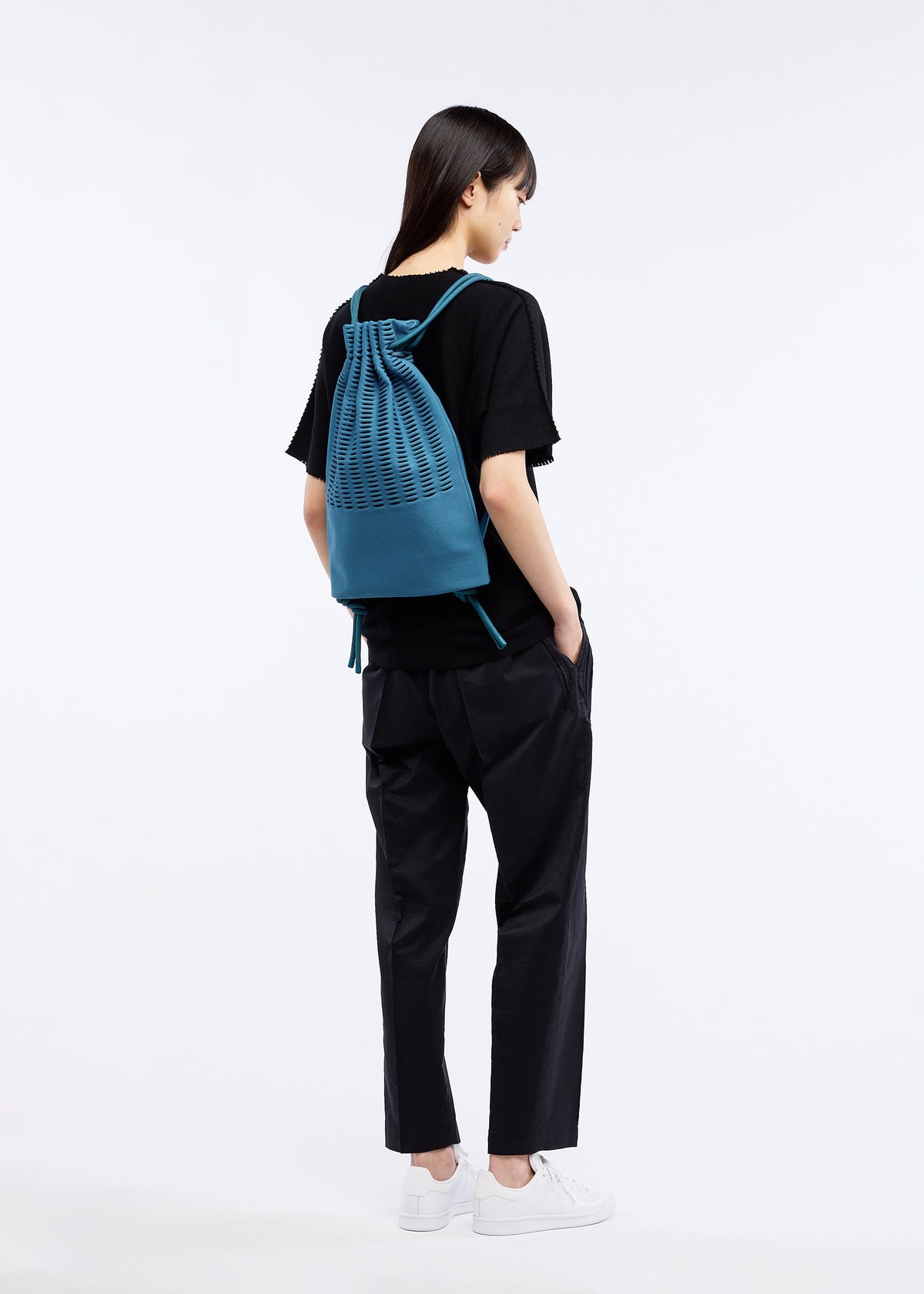 A model wears the GOOD GOODS ISSEY MIYAKE MOKKO KNAPSACK bag.