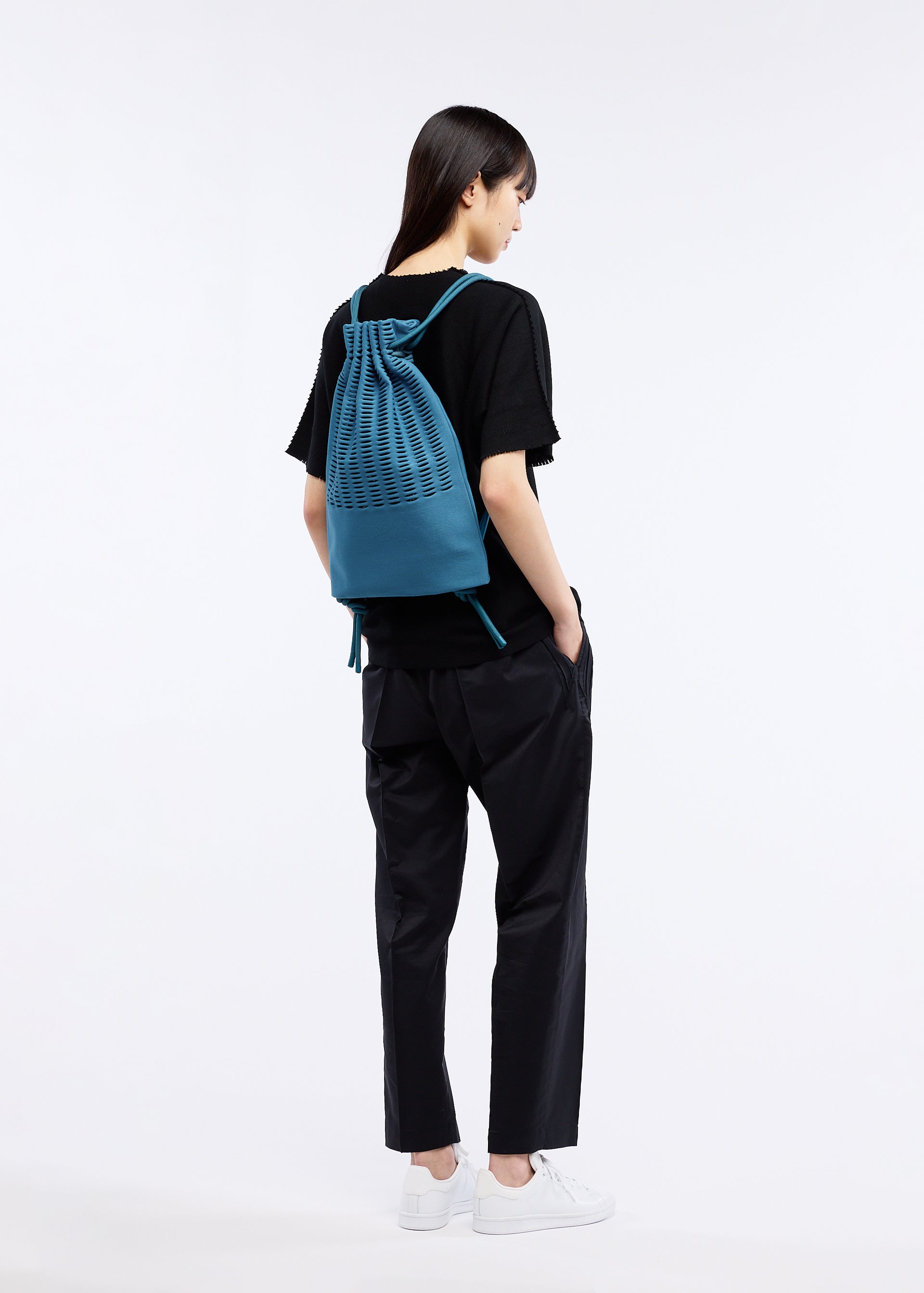A model wears the GOOD GOODS ISSEY MIYAKE MOKKO KNAPSACK bag.