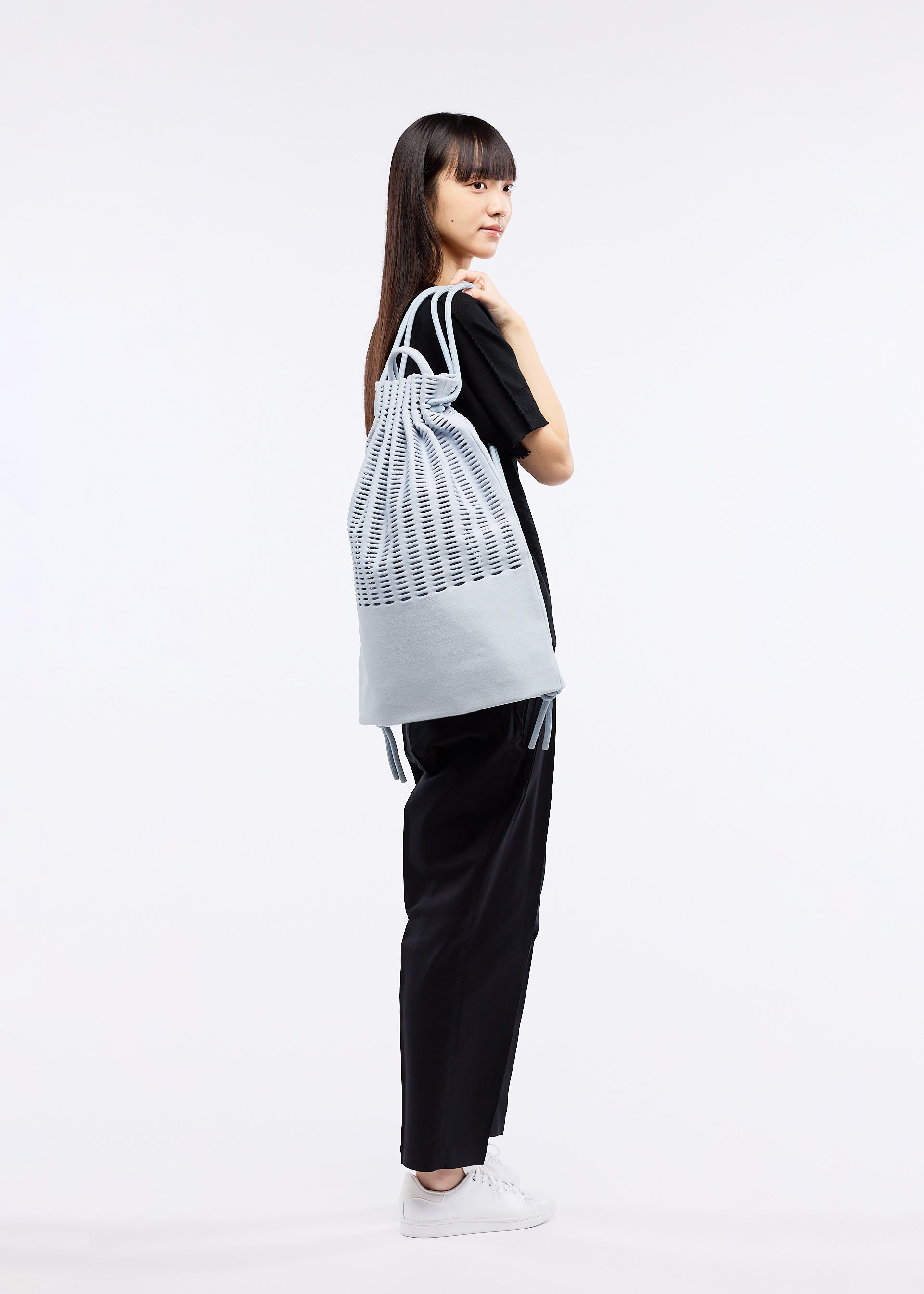 A model wears the GOOD GOODS ISSEY MIYAKE MOKKO KNAPSACK bag.