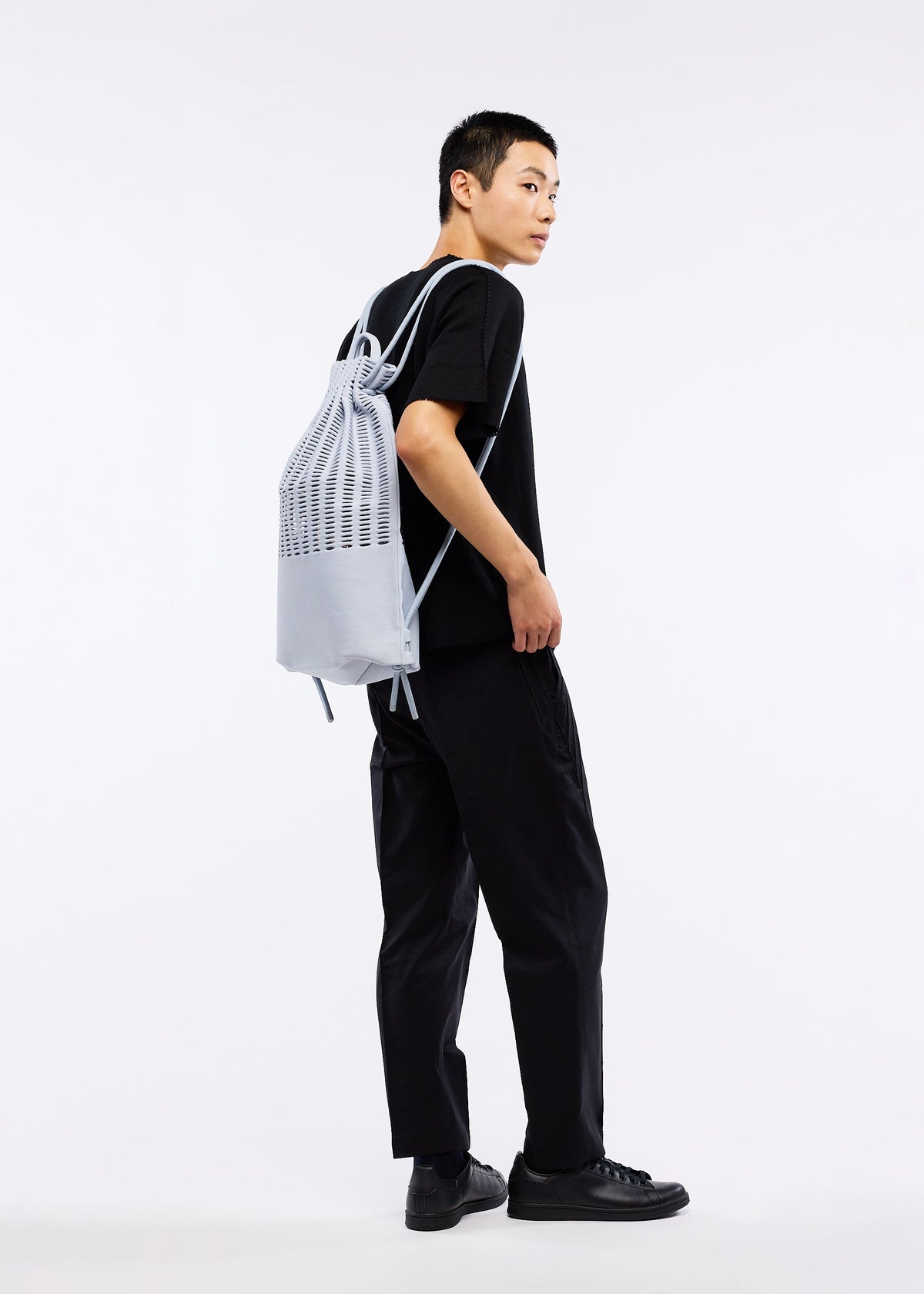 A model wears the GOOD GOODS ISSEY MIYAKE MOKKO KNAPSACK bag.
