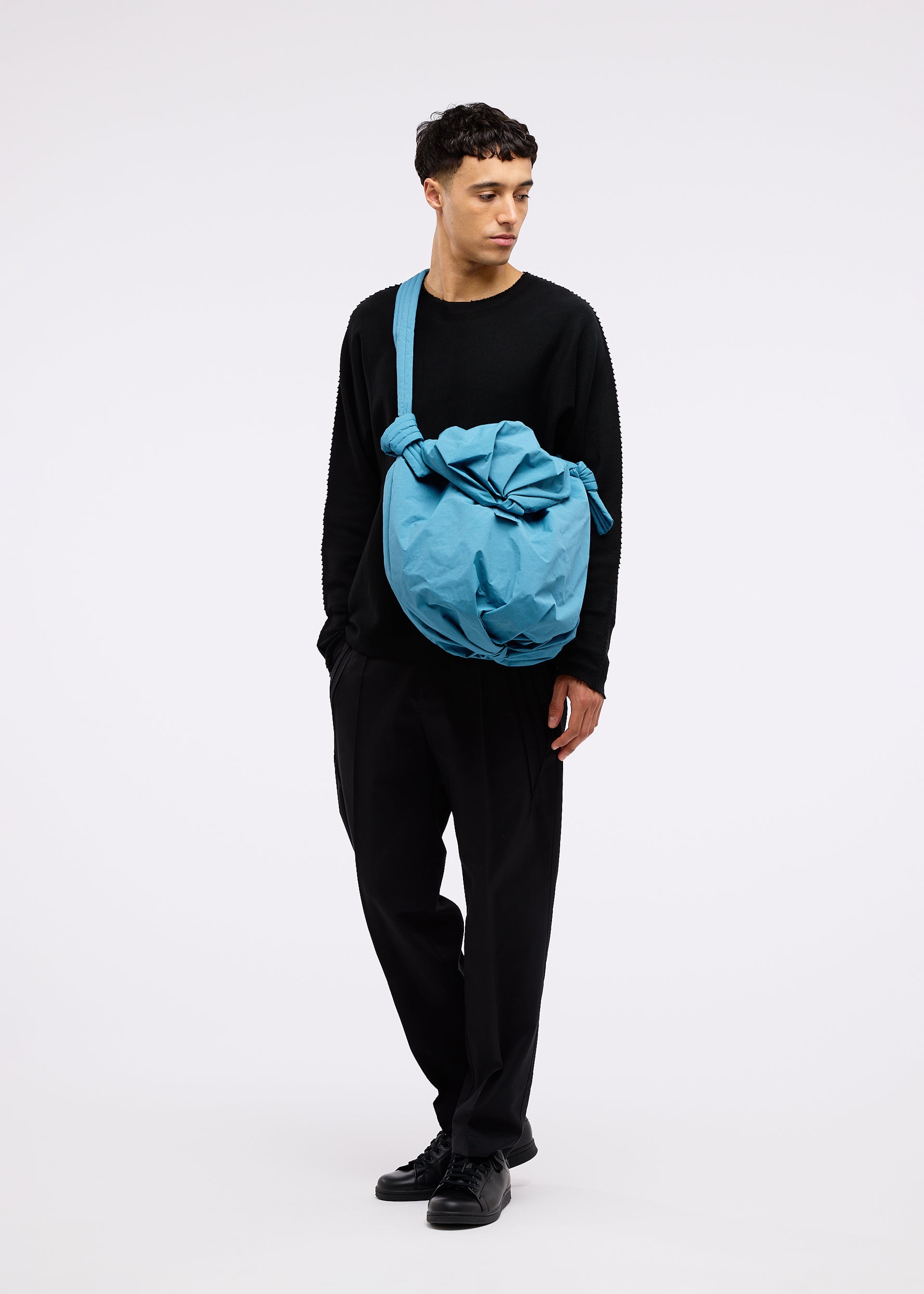 A model wears the GOOD GOODS ISSEY MIYAKE FUWA FUWA bag.