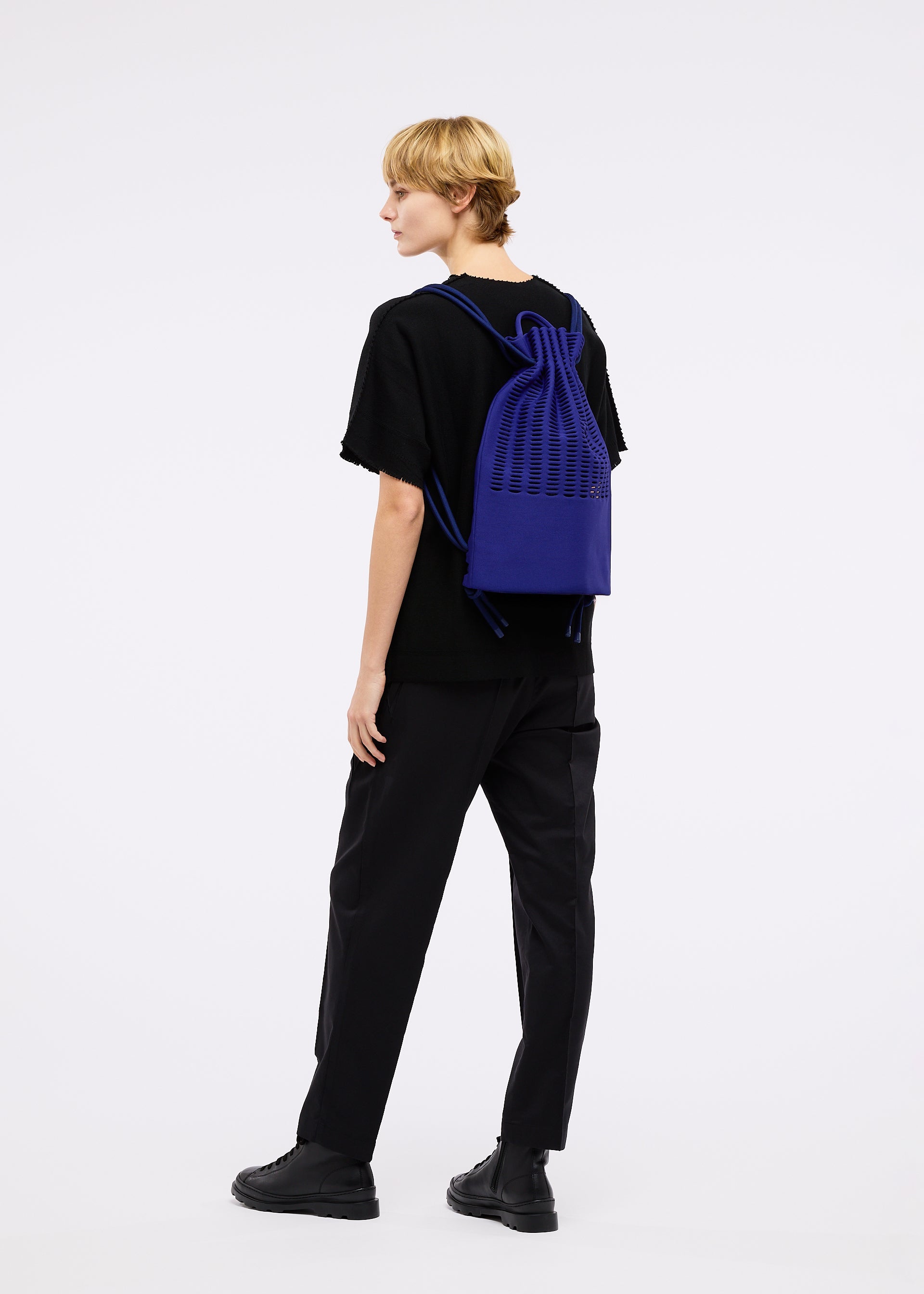 A model wears the GOOD GOODS ISSEY MIYAKE MOKKO KNAPSACK bag.