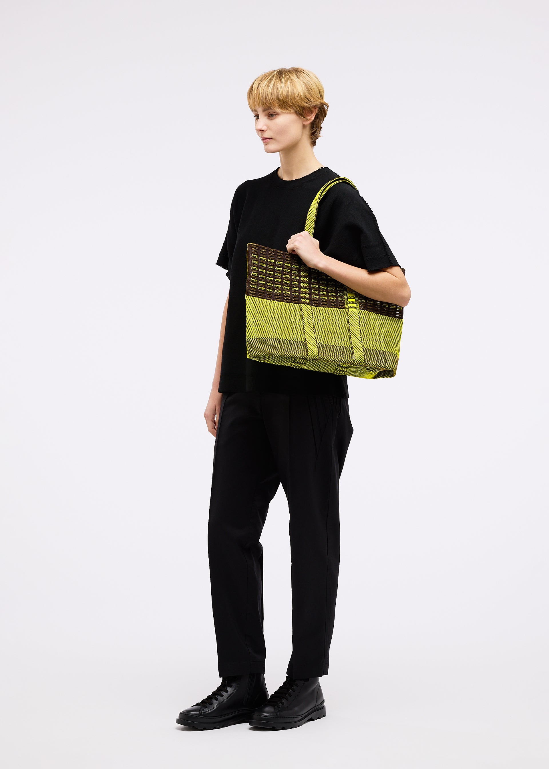 A model wears the GOOD GOODS ISSEY MIYAKE MOKKO TOTE MIX bag.