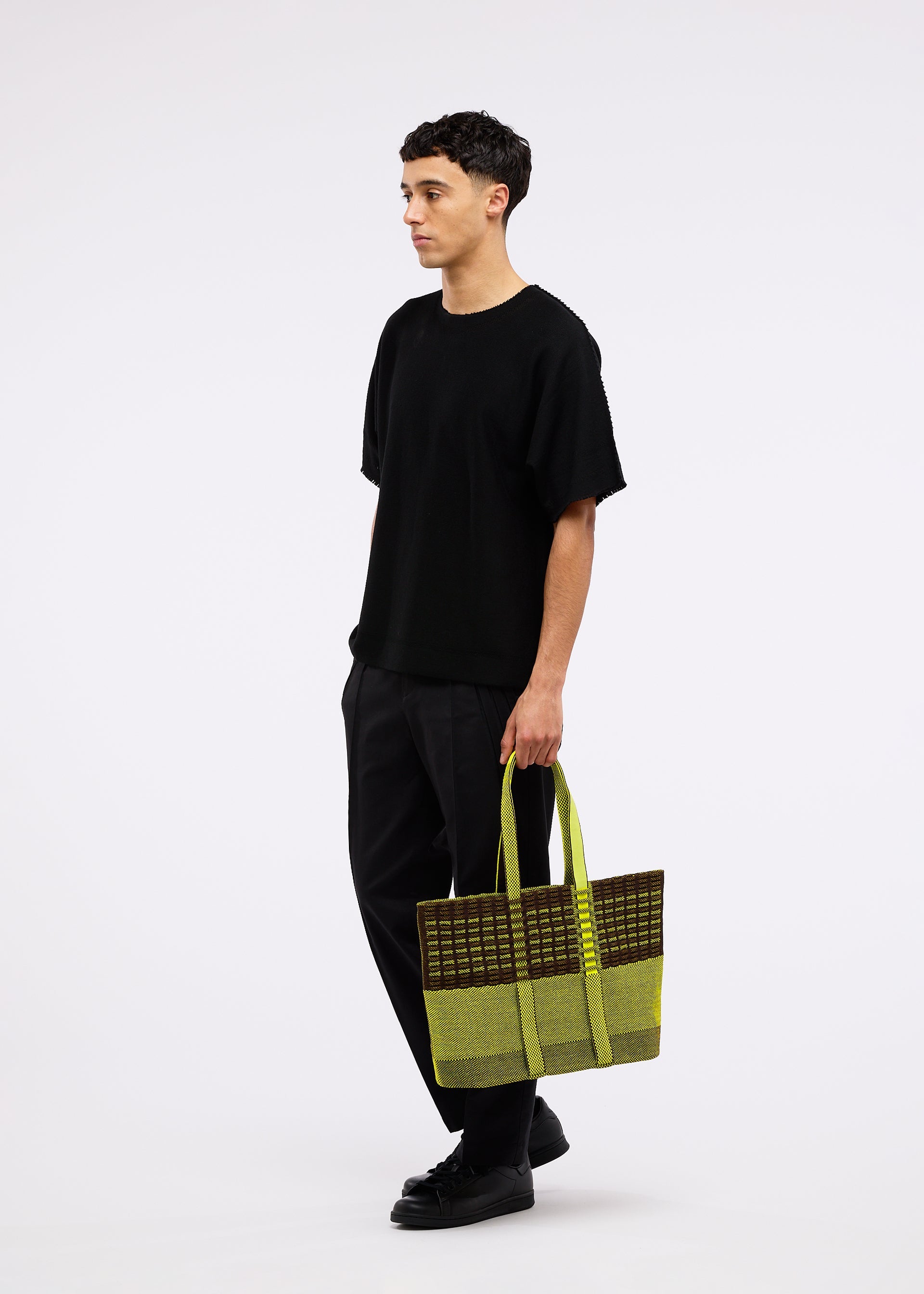 A model wears the GOOD GOODS ISSEY MIYAKE MOKKO TOTE MIX bag.