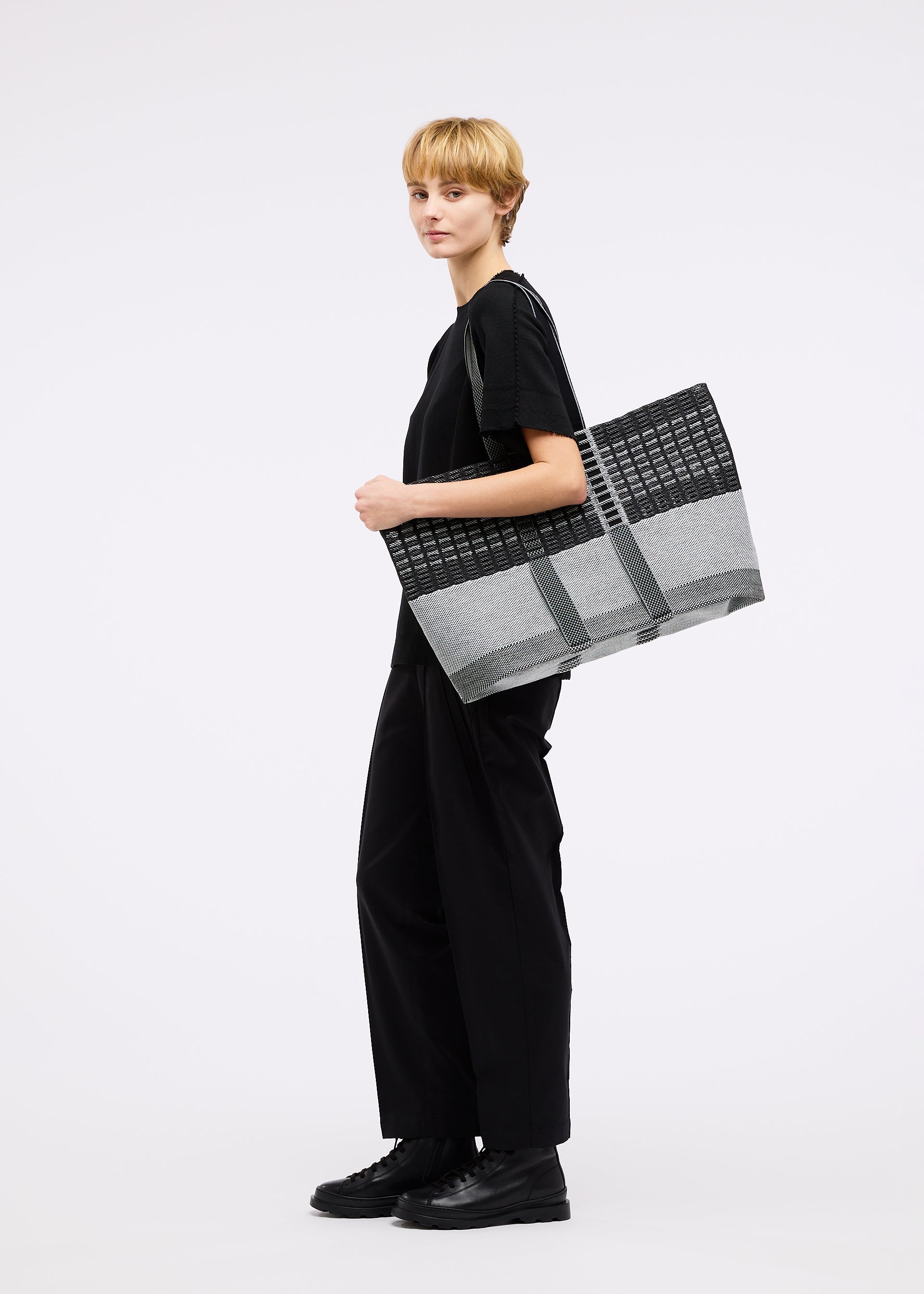 A model wears the GOOD GOODS ISSEY MIYAKE MOKKO TOTE MIX bag.
