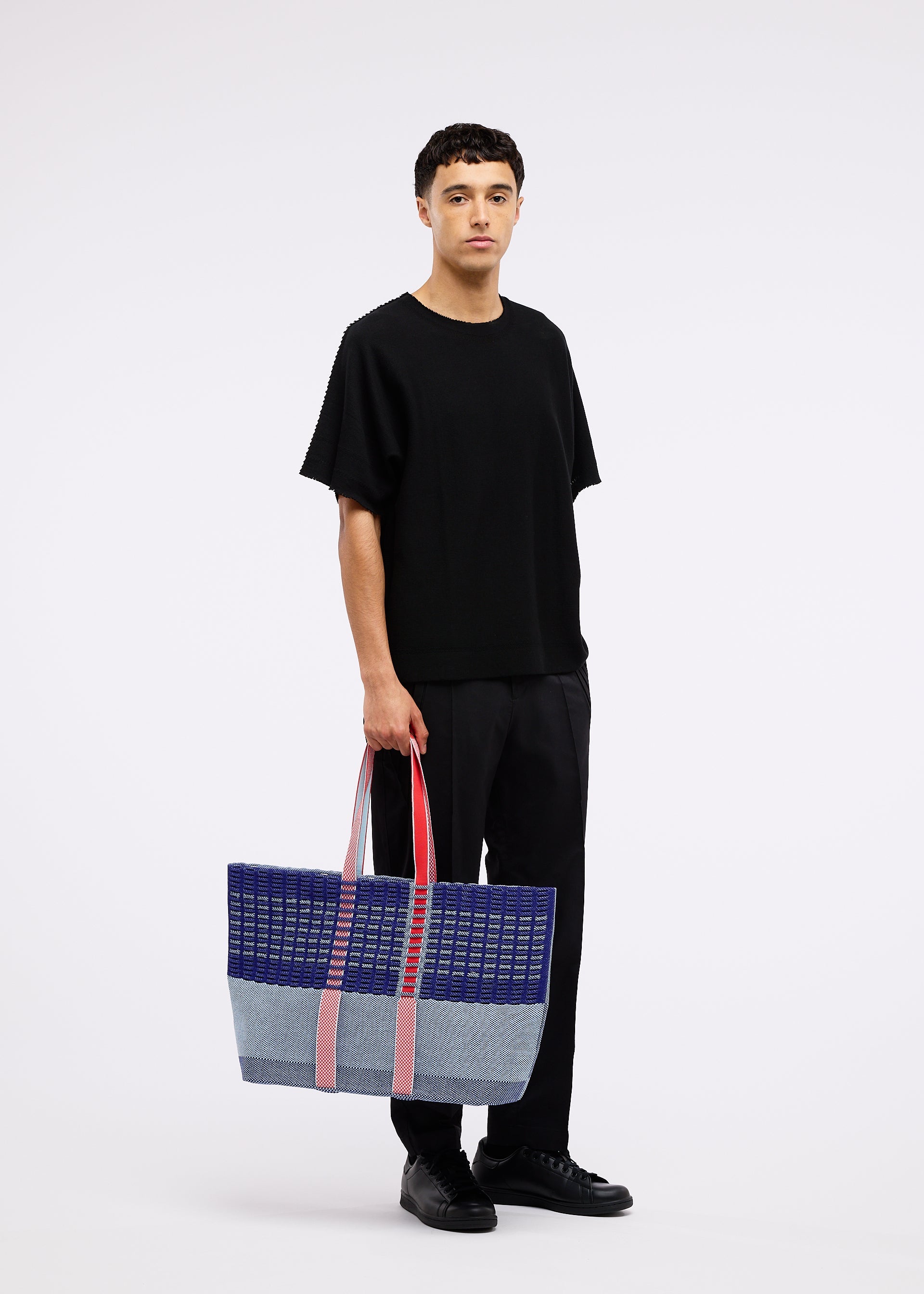 A model wears the GOOD GOODS ISSEY MIYAKE MOKKO TOTE MIX bag.