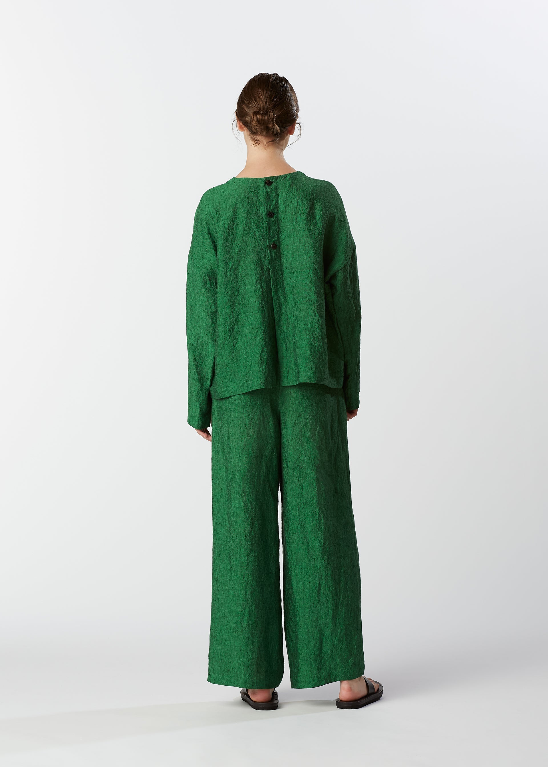 A model wears the HAAT GLOSSY LINEN trousers.