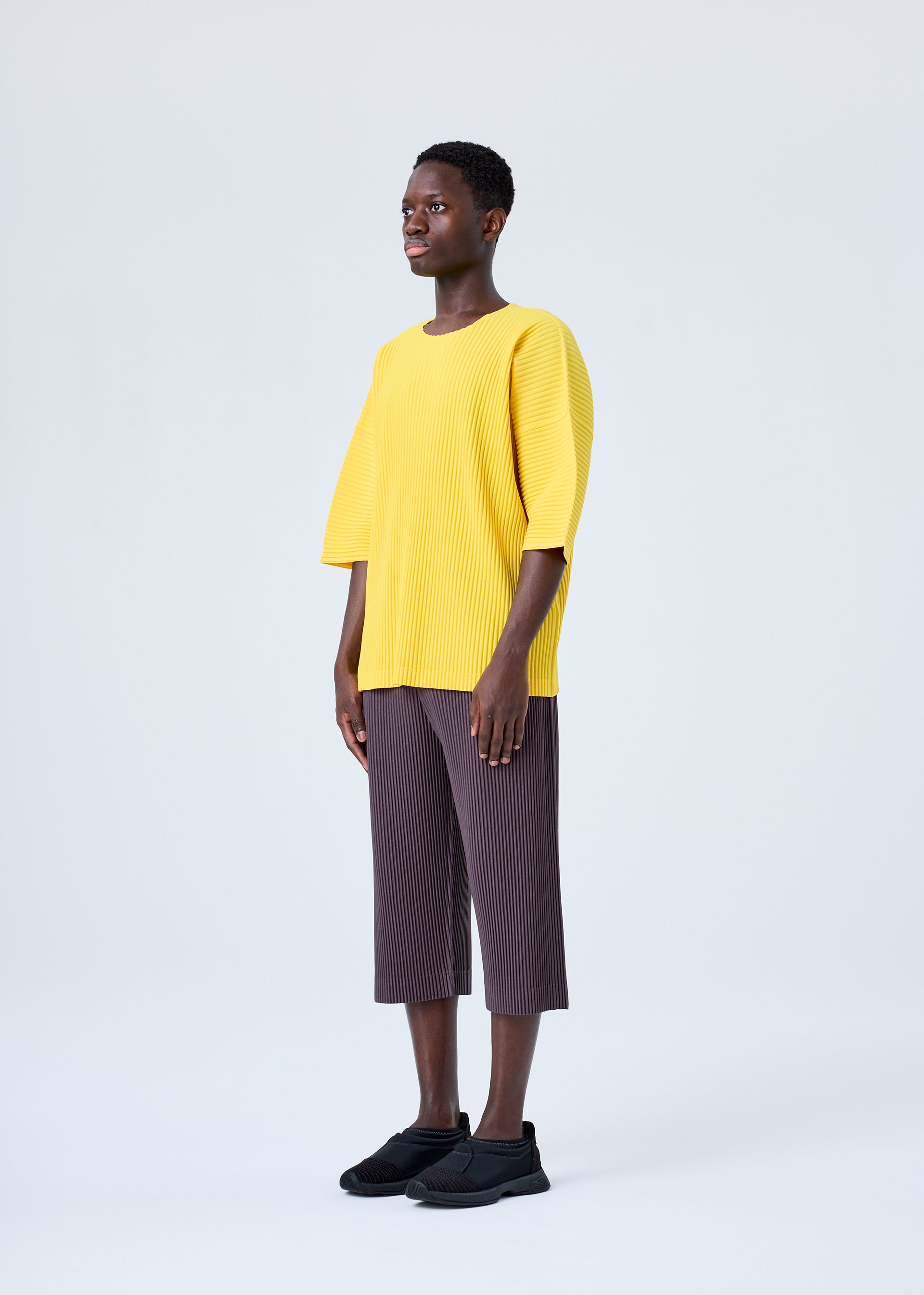 A model wears the HOMME PLISSÉ ISSEY MIYAKE MC JULY top