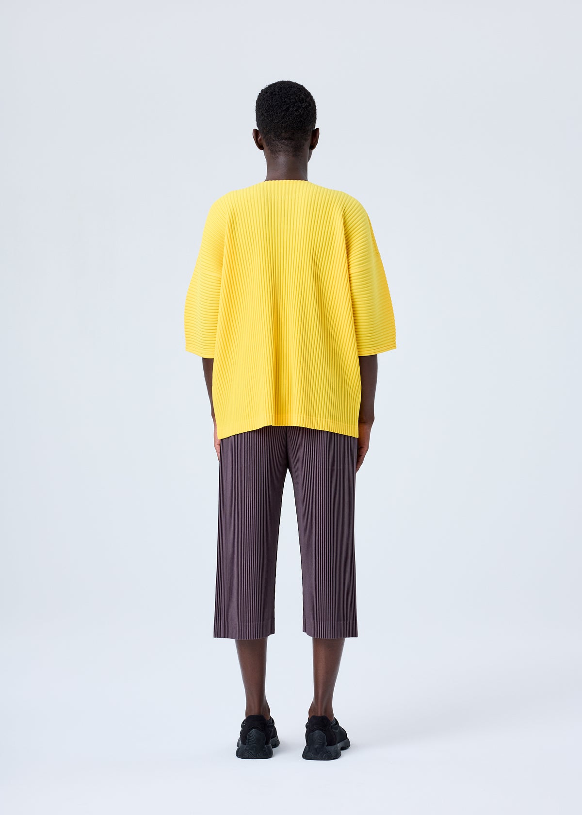 A model wears the HOMME PLISSÉ ISSEY MIYAKE MC JULY top