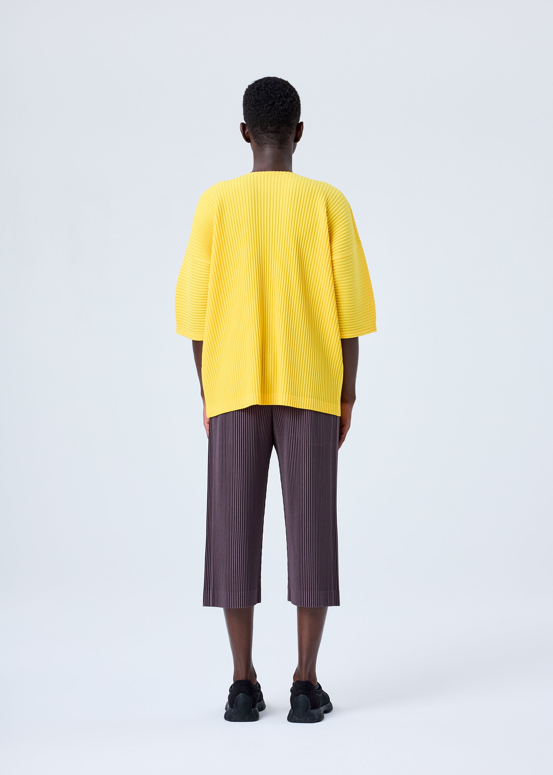A model wears the HOMME PLISSÉ ISSEY MIYAKE MC JULY top