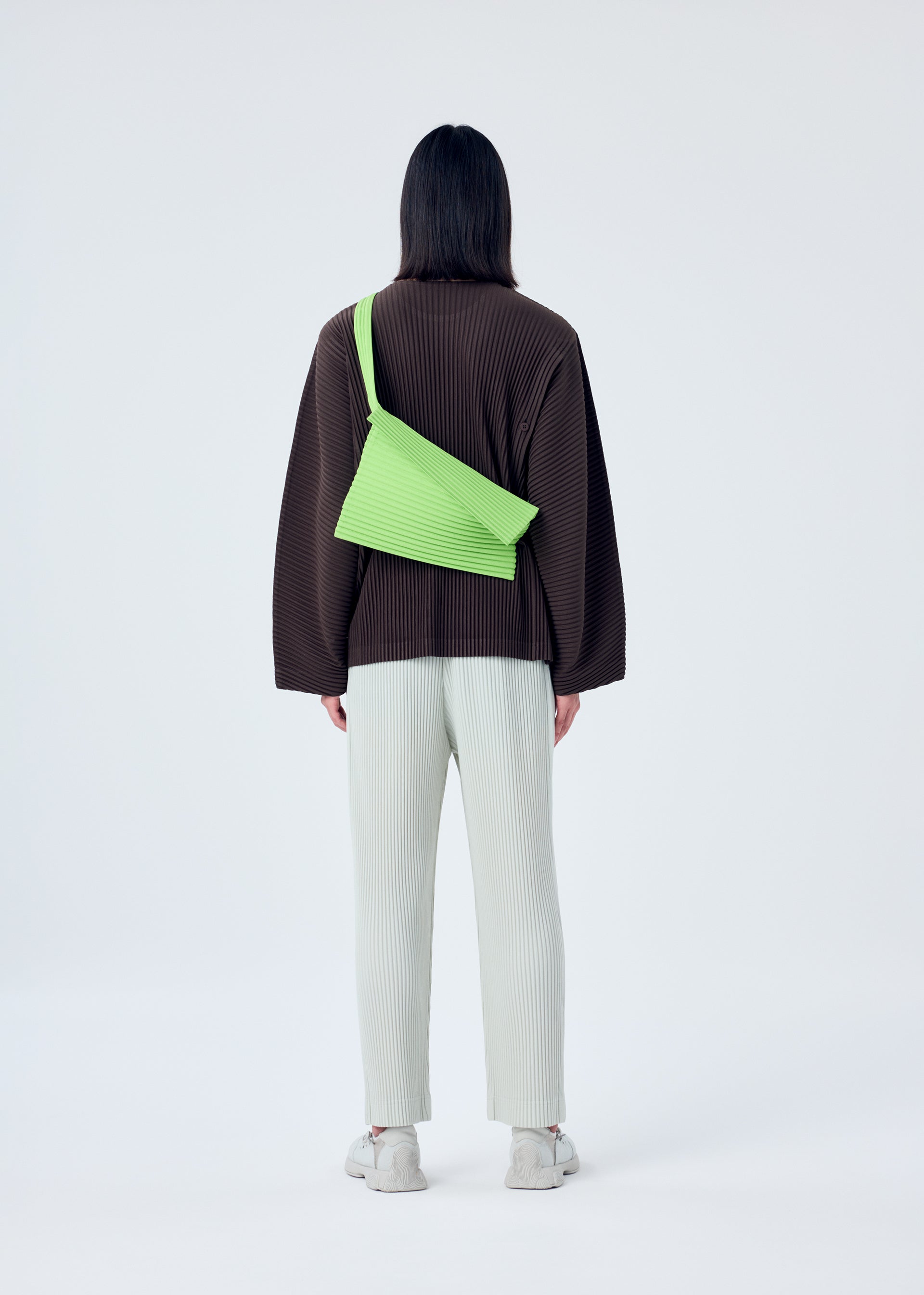 A model wears the HOMME PLISSÉ ISSEY MIYAKE OVERLAP bag.