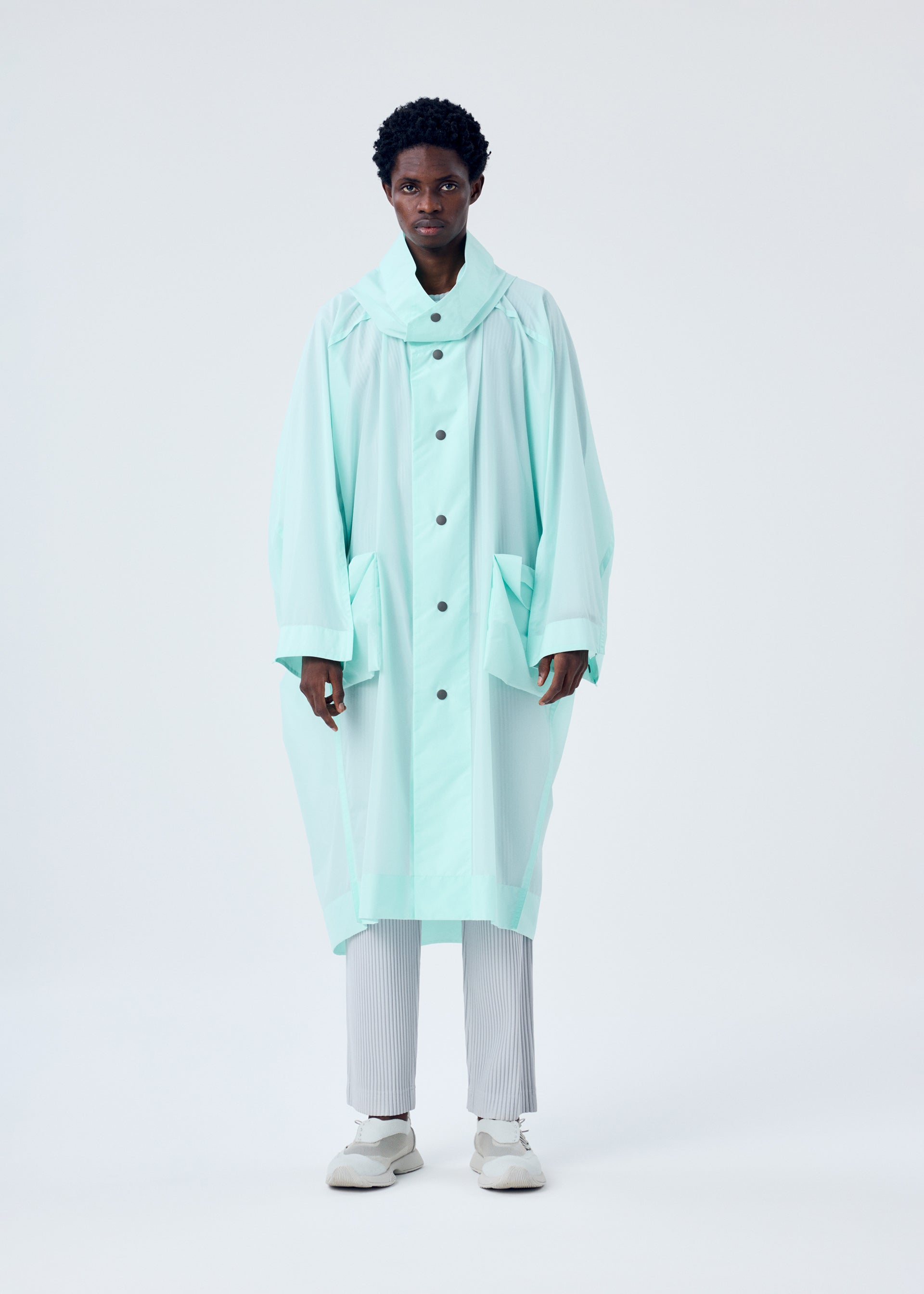 A model wears the HOMME PLISSÉ ISSEY MIYAKE KITE COAT coat.