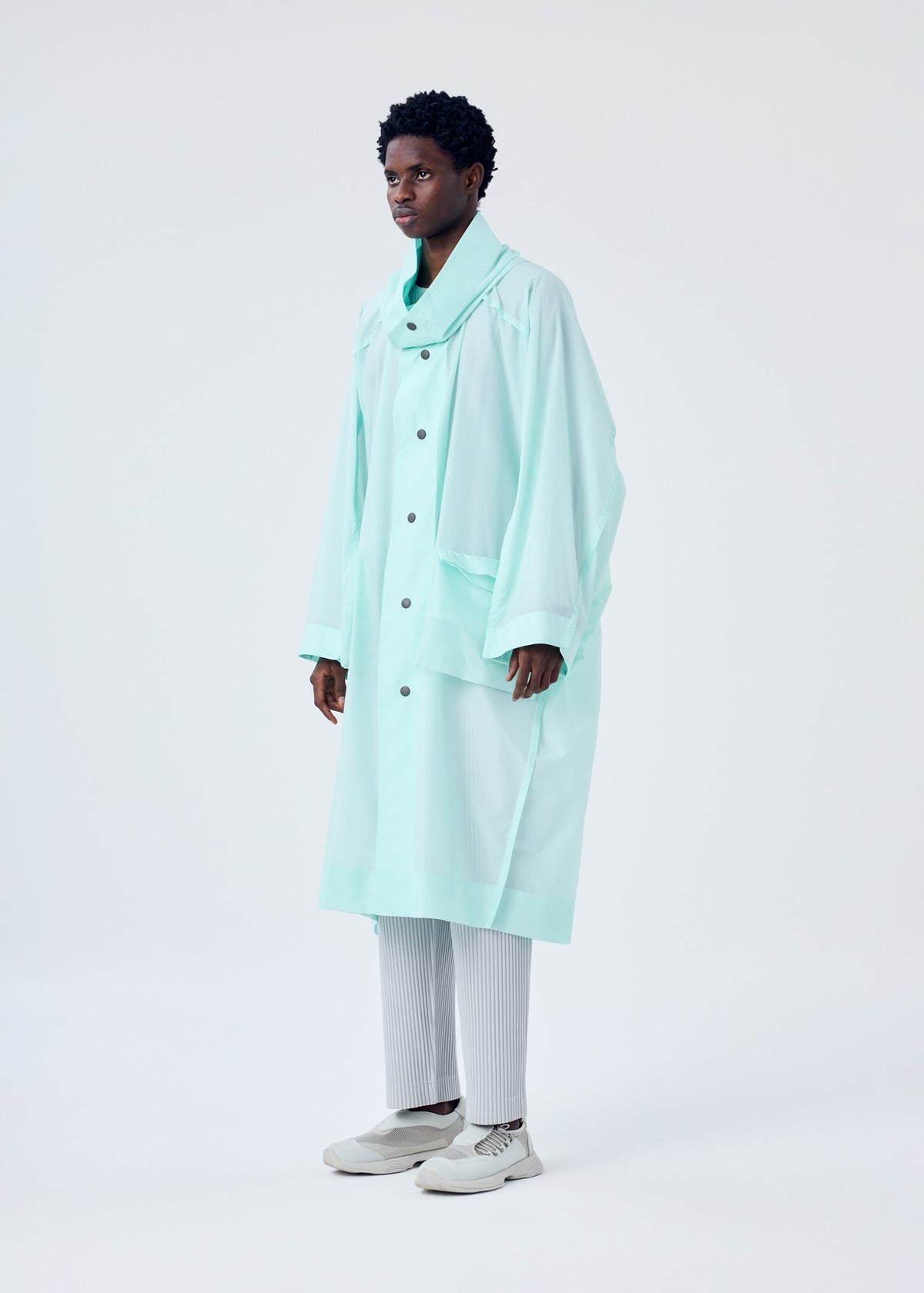 A model wears the HOMME PLISSÉ ISSEY MIYAKE KITE COAT coat.