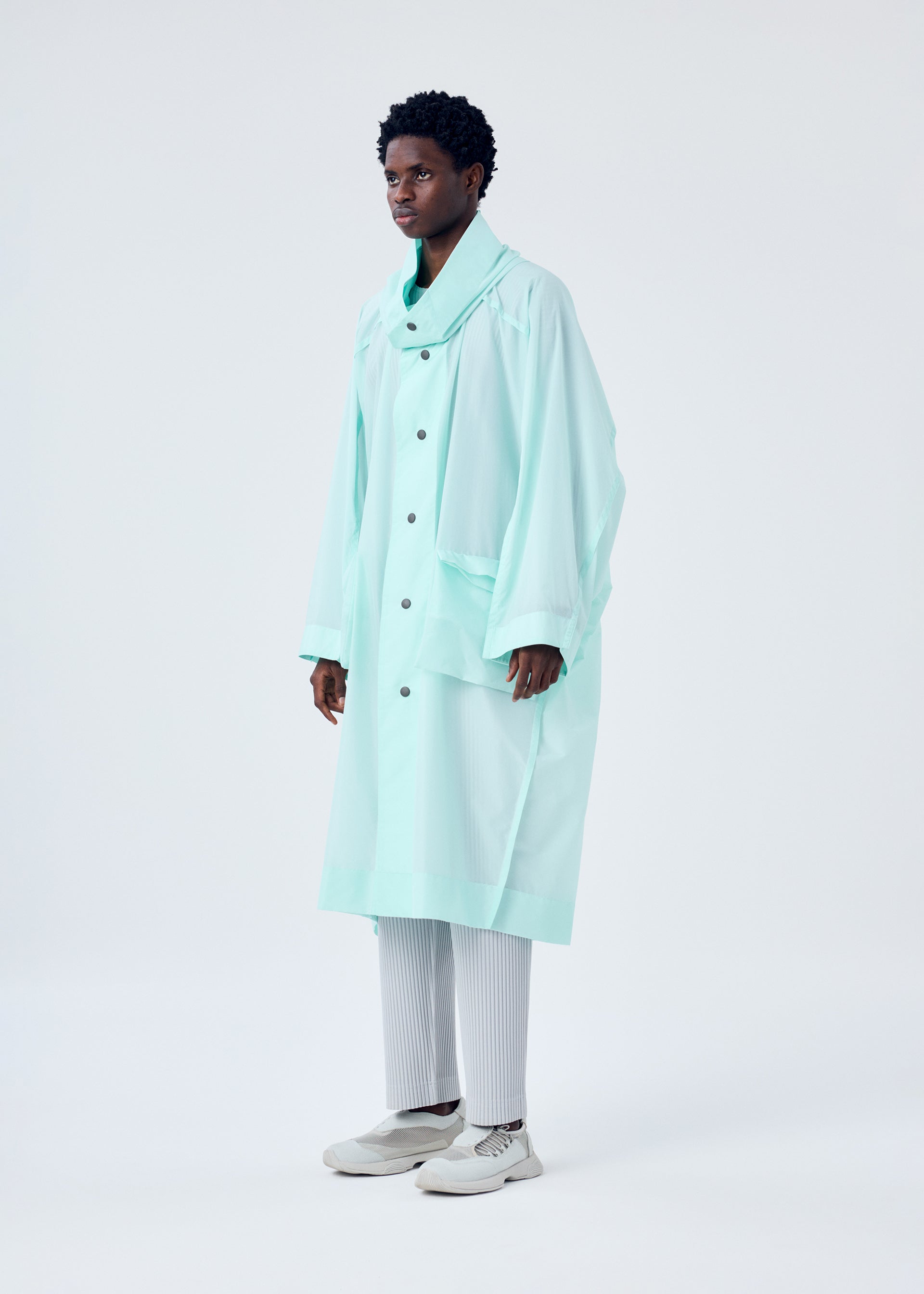A model wears the HOMME PLISSÉ ISSEY MIYAKE KITE COAT coat.