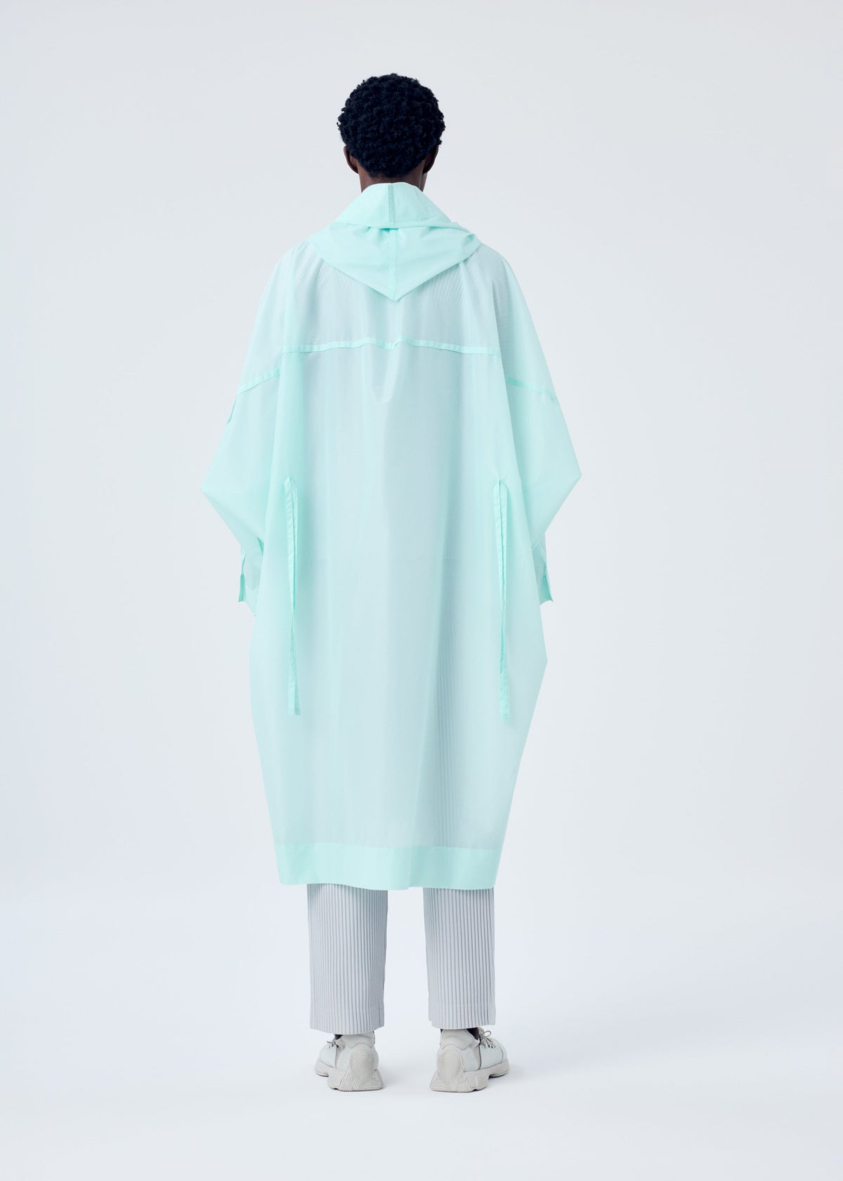 A model wears the HOMME PLISSÉ ISSEY MIYAKE KITE COAT coat.