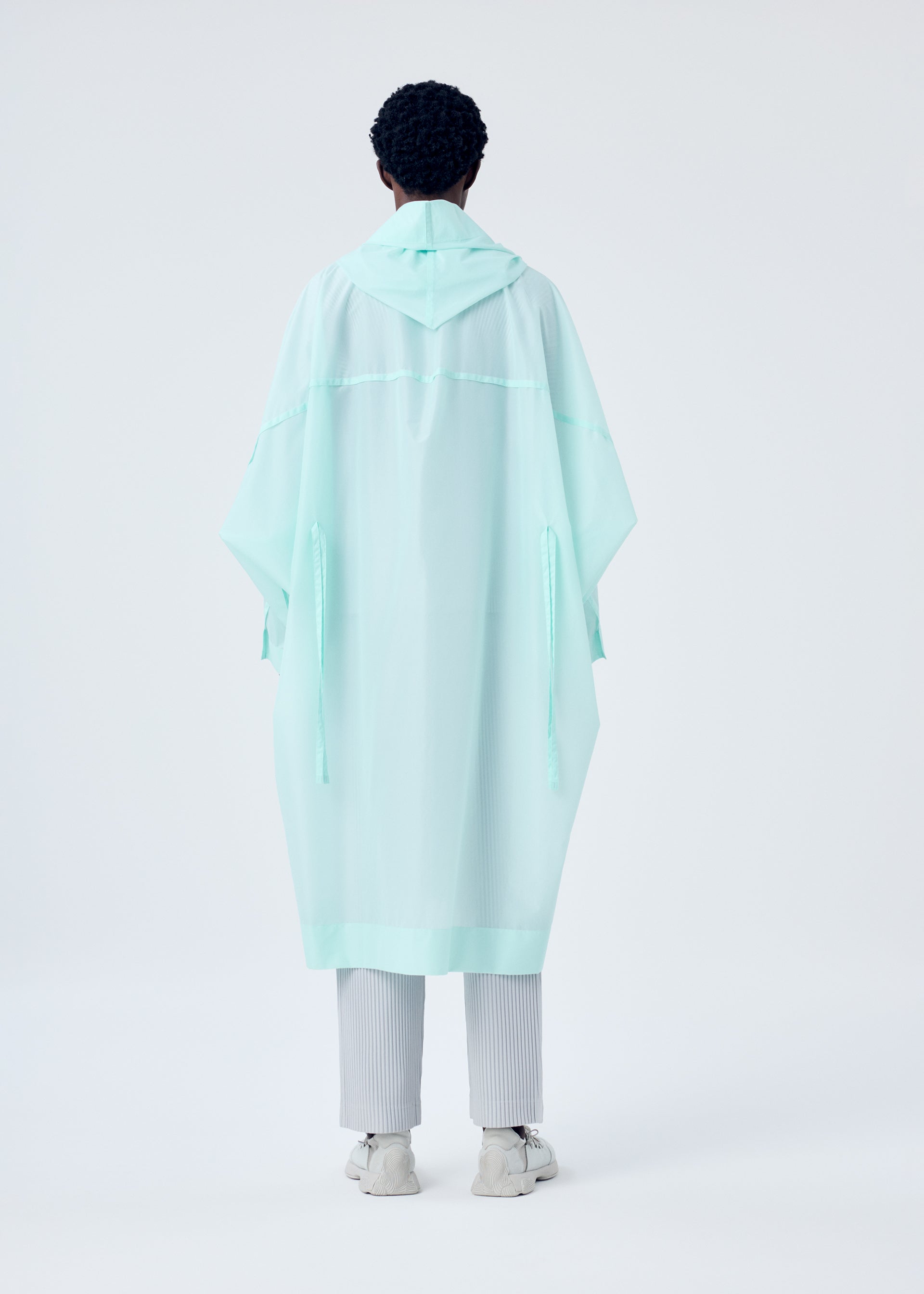 A model wears the HOMME PLISSÉ ISSEY MIYAKE KITE COAT coat.
