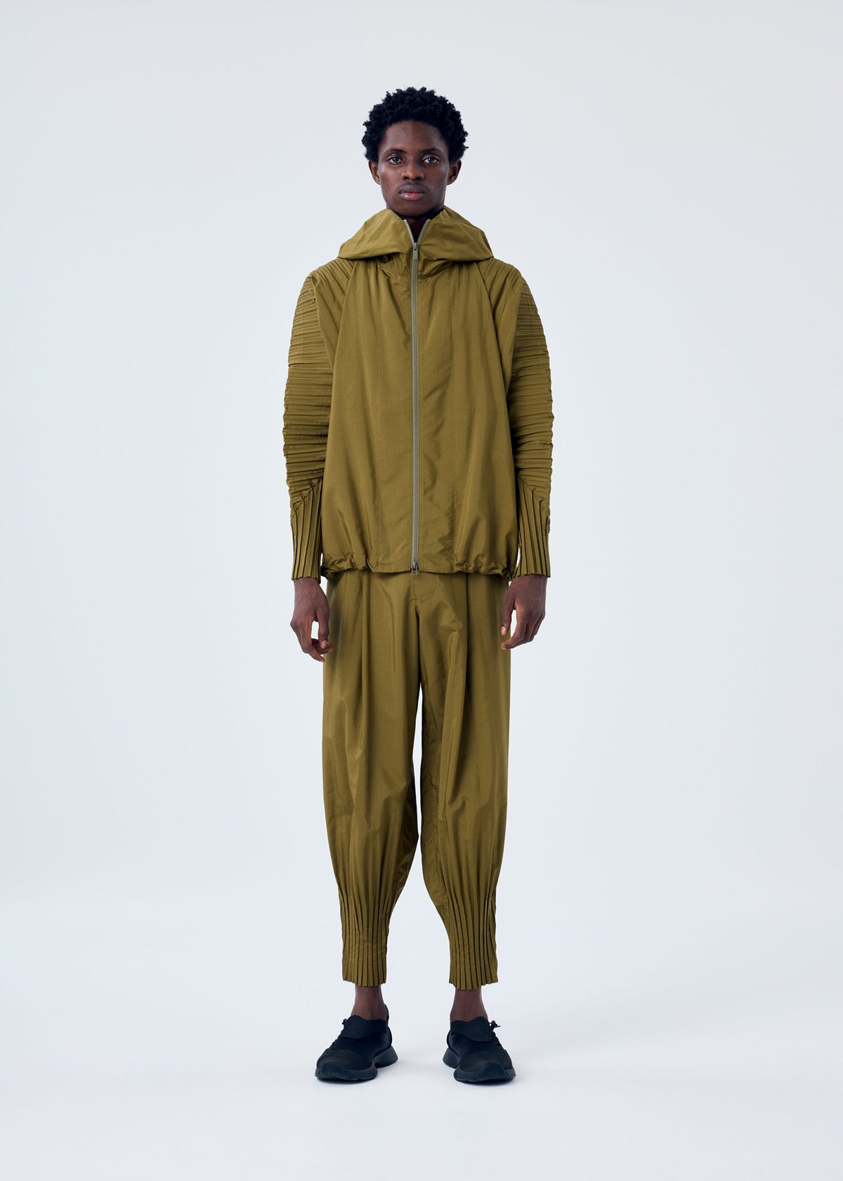 A model wears the HOMME PLISSÉ ISSEY MIYAKE CASCADE trousers.