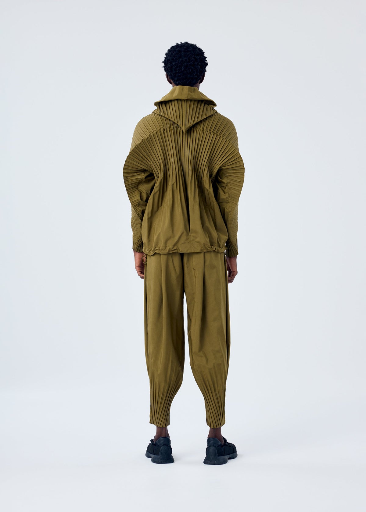 A model wears the HOMME PLISSÉ ISSEY MIYAKE CASCADE trousers.