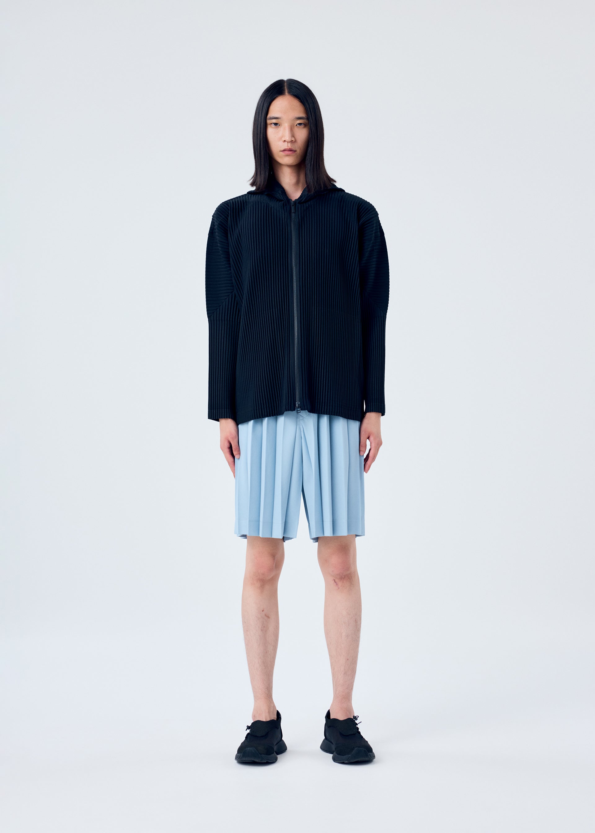 A model wears the HOMME PLISSÉ ISSEY MIYAKE EDGE ENSEMBLE trousers.