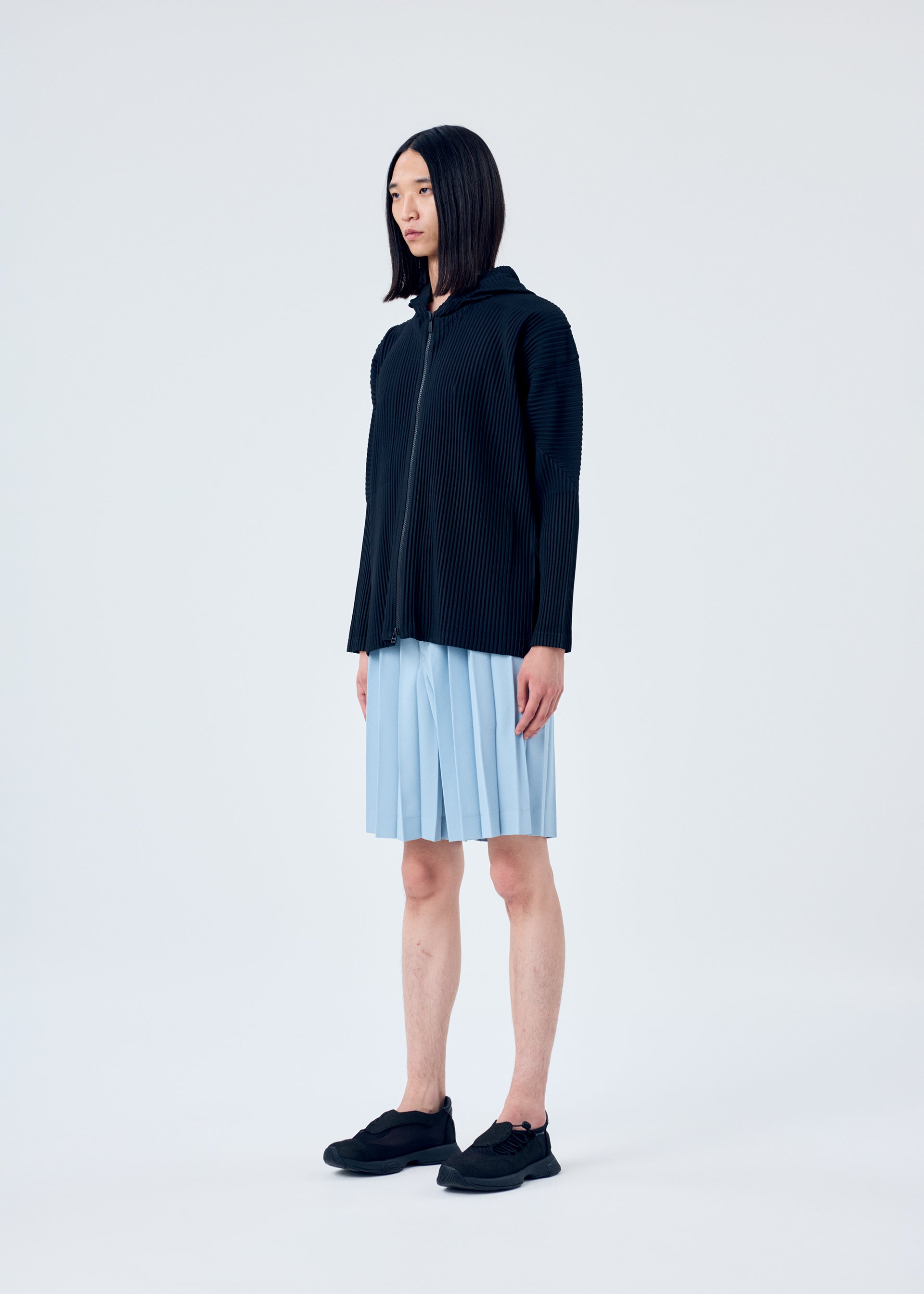 A model wears the HOMME PLISSÉ ISSEY MIYAKE EDGE ENSEMBLE trousers.