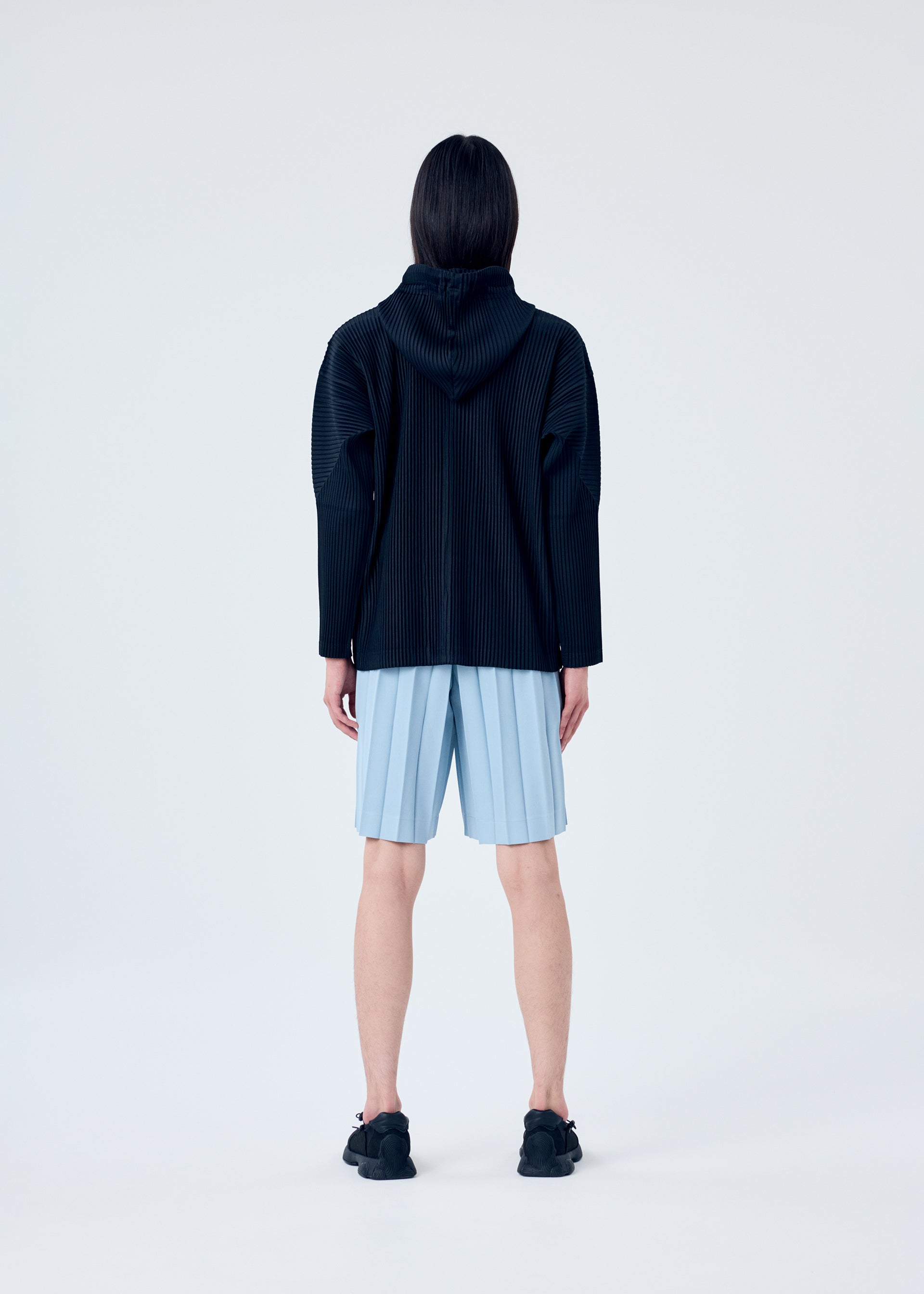 A model wears the HOMME PLISSÉ ISSEY MIYAKE EDGE ENSEMBLE trousers.