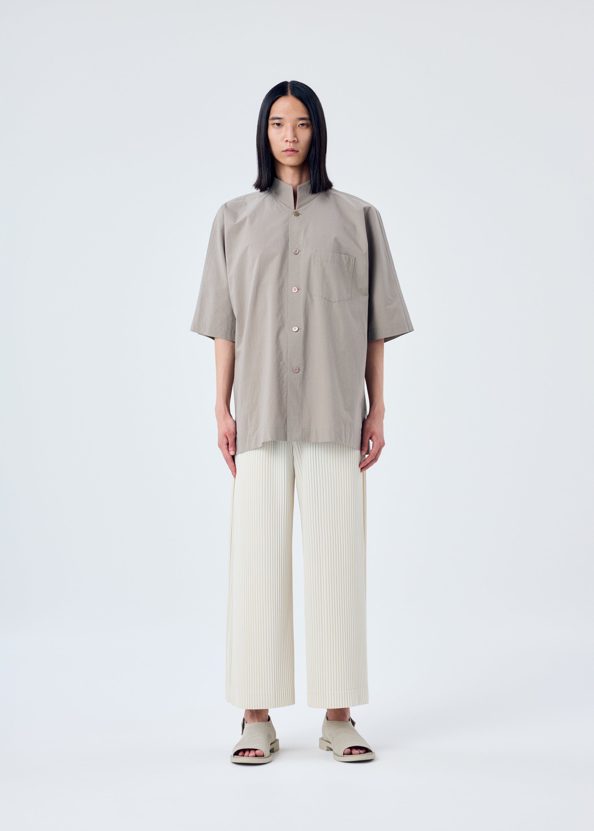 A model wears the HOMME PLISSÉ ISSEY MIYAKE MC MAY trousers.