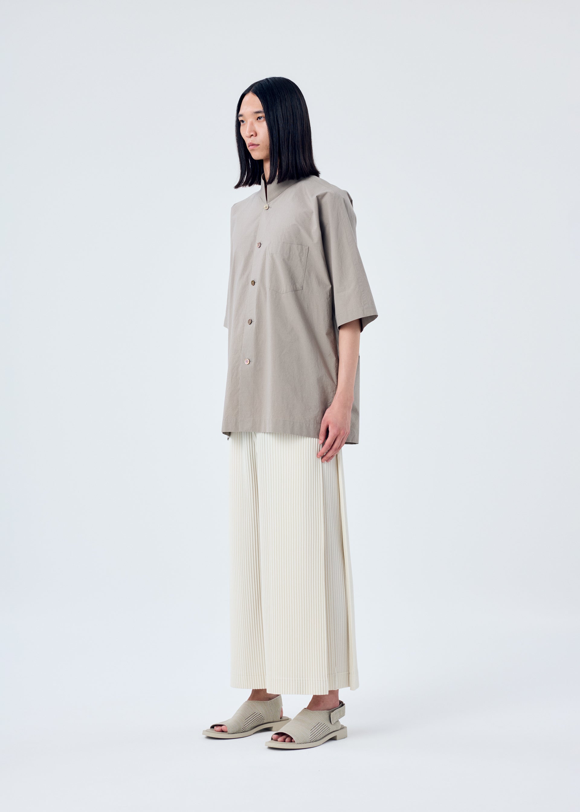 A model wears the HOMME PLISSÉ ISSEY MIYAKE MC MAY trousers.