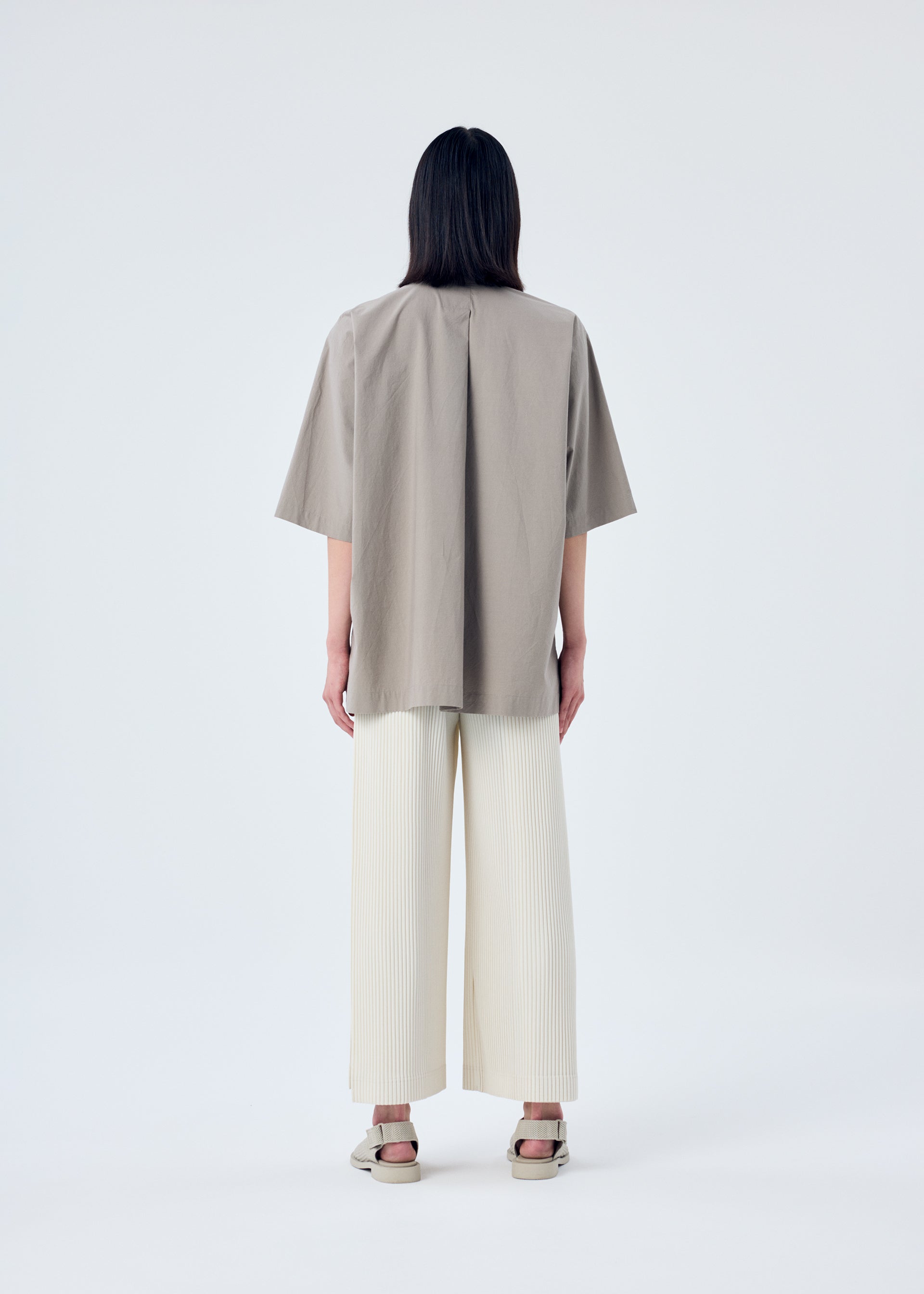 A model wears the HOMME PLISSÉ ISSEY MIYAKE MC MAY trousers.