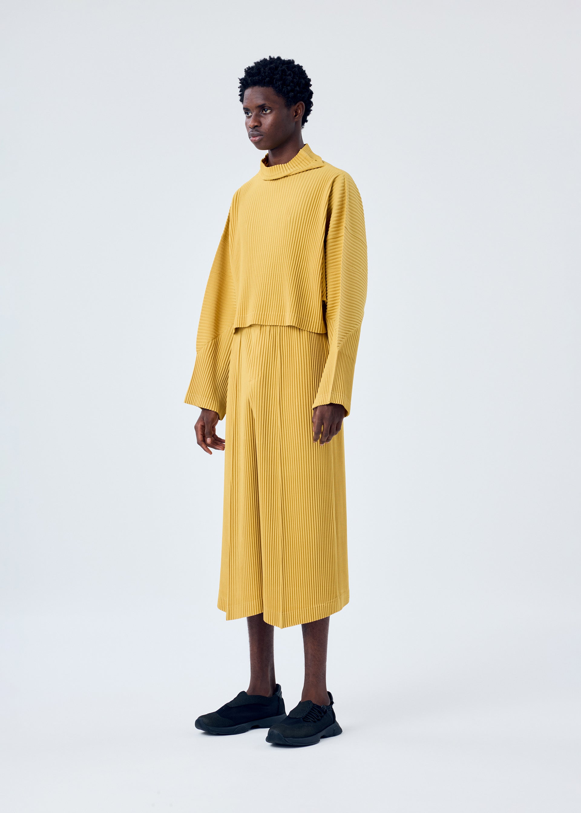 A model wears the HOMME PLISSÉ ISSEY MIYAKE MC JUNE trousers.