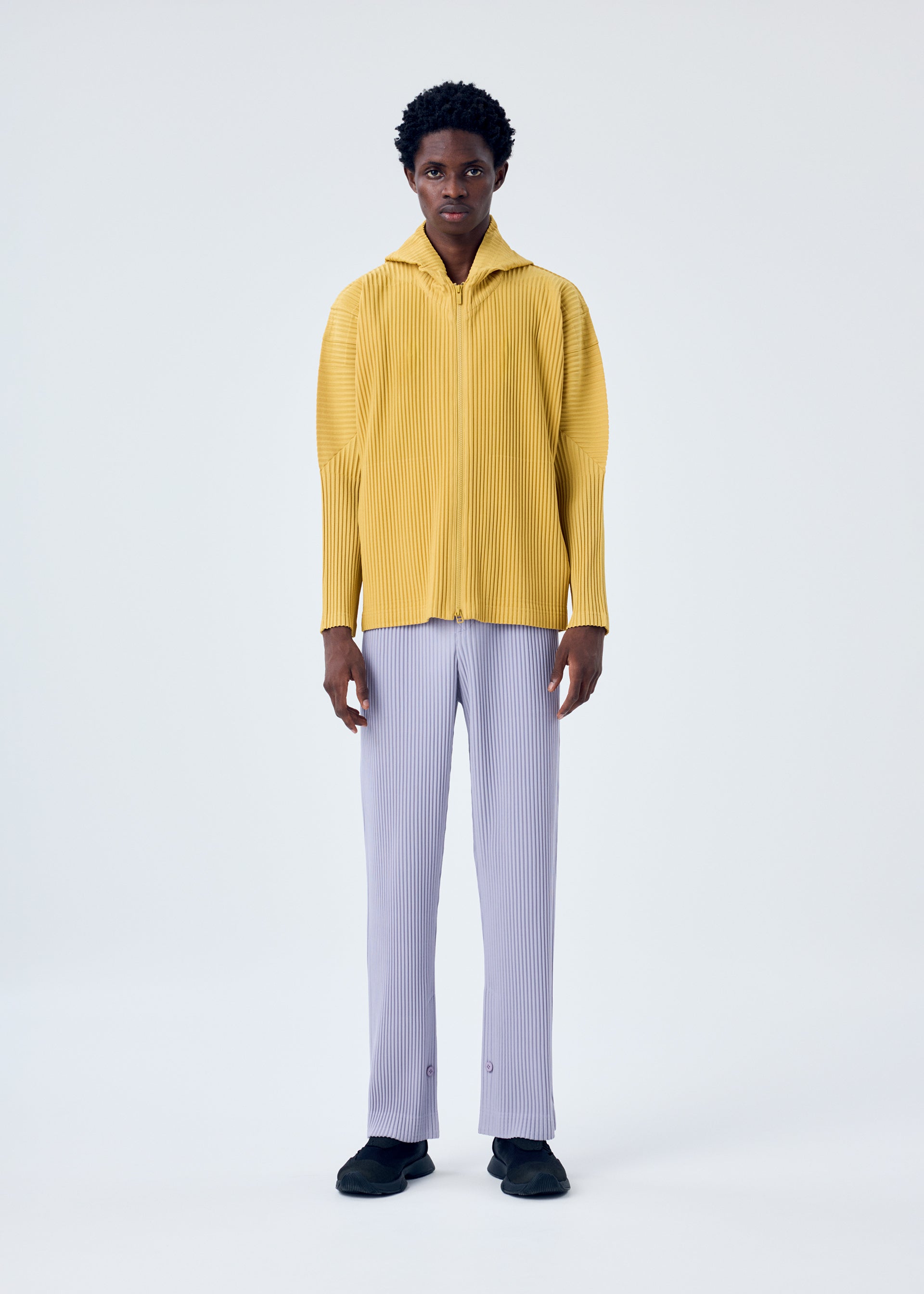 A model wears the HOMME PLISSÉ ISSEY MIYAKE MC JUNE trousers.