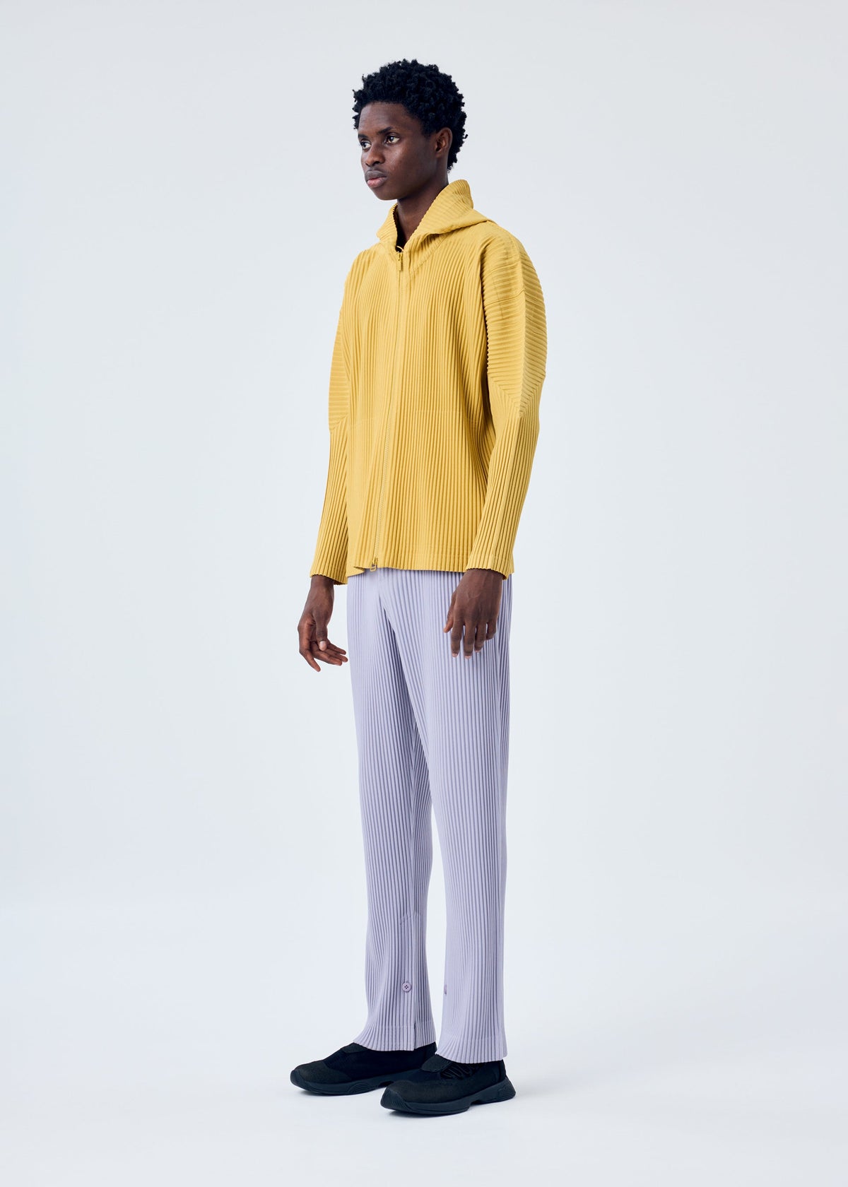 A model wears the HOMME PLISSÉ ISSEY MIYAKE MC JUNE trousers.