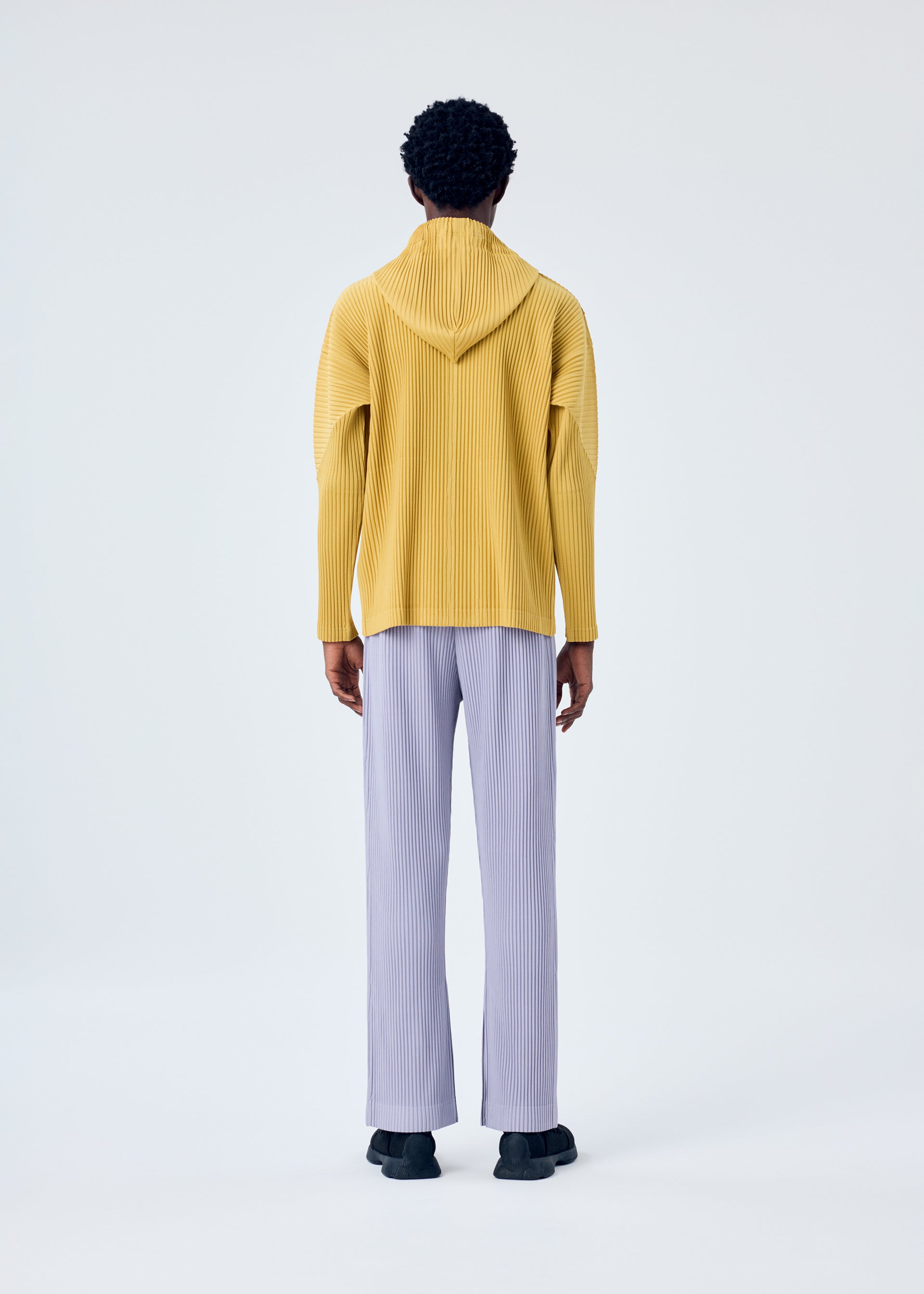 A model wears the HOMME PLISSÉ ISSEY MIYAKE MC JUNE trousers.