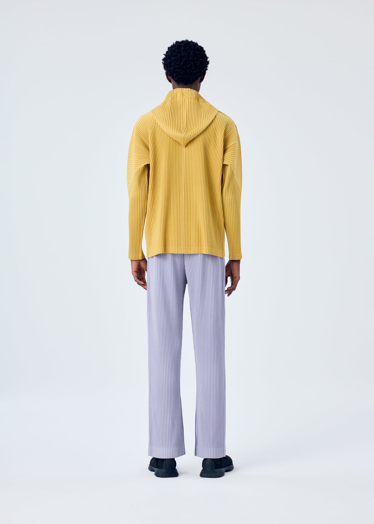 A model wears the HOMME PLISSÉ ISSEY MIYAKE MC JUNE trousers.