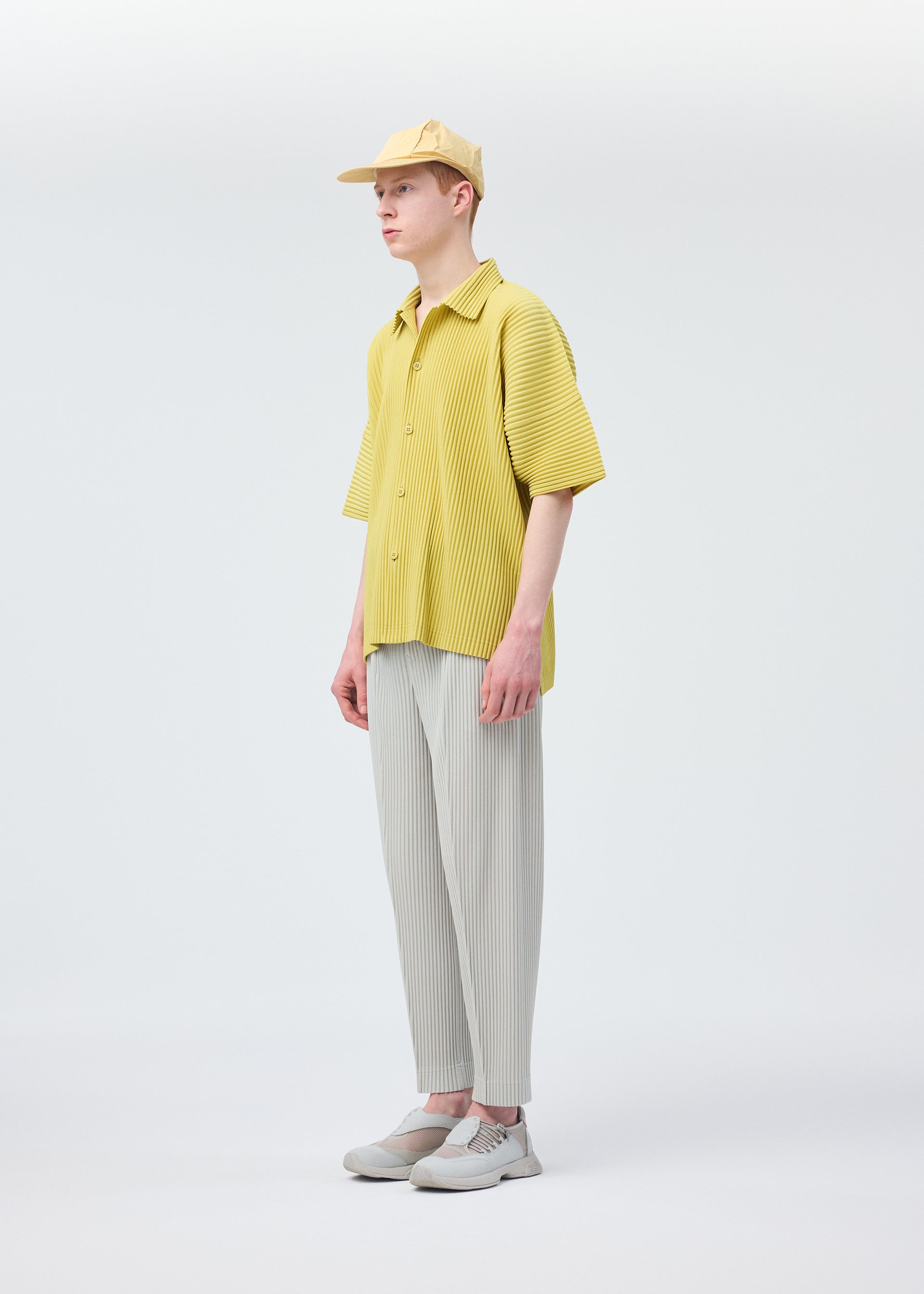 A model wears the HOMME PLISSÉ ISSEY MIYAKE STONE CAP hat.