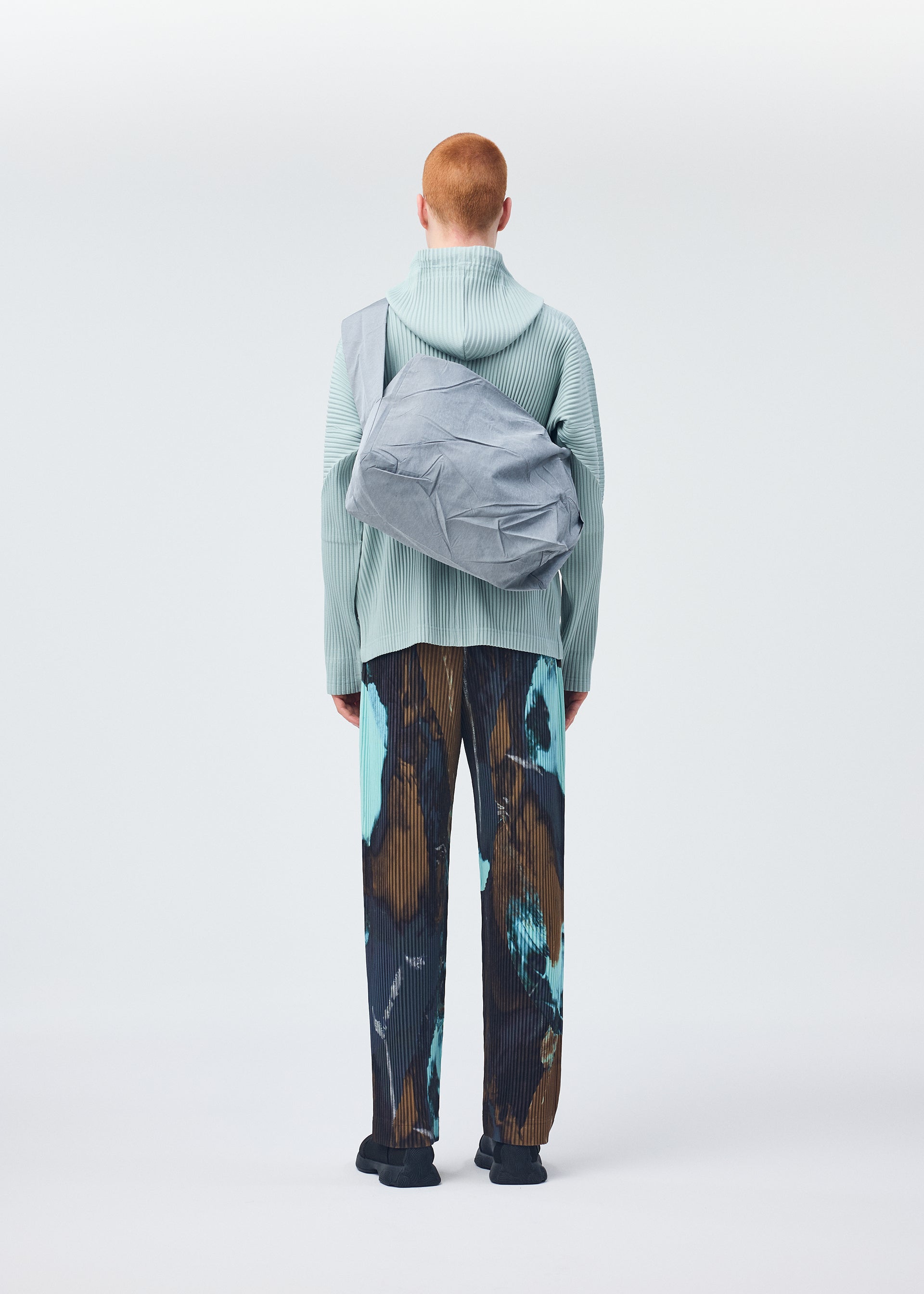 A model wears the HOMME PLISSÉ ISSEY MIYAKE STONE BAG bag.