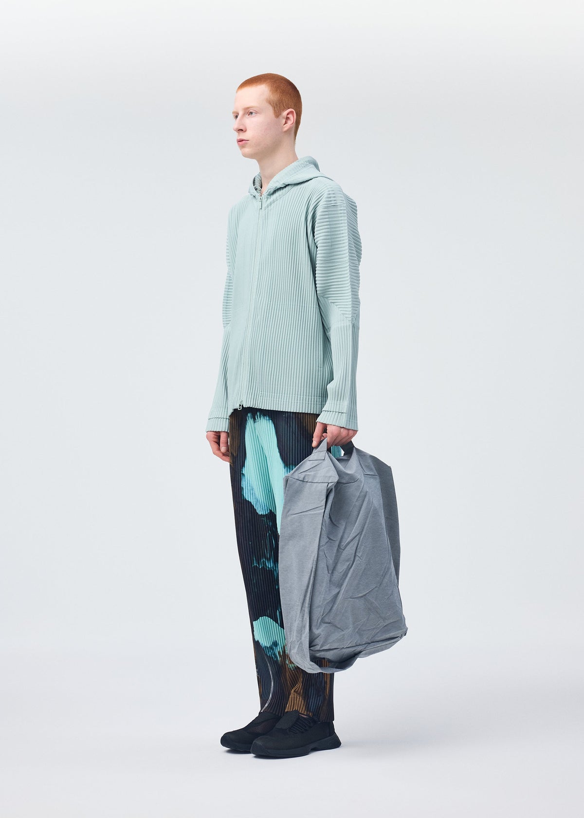 A model wears the HOMME PLISSÉ ISSEY MIYAKE STONE BAG bag.