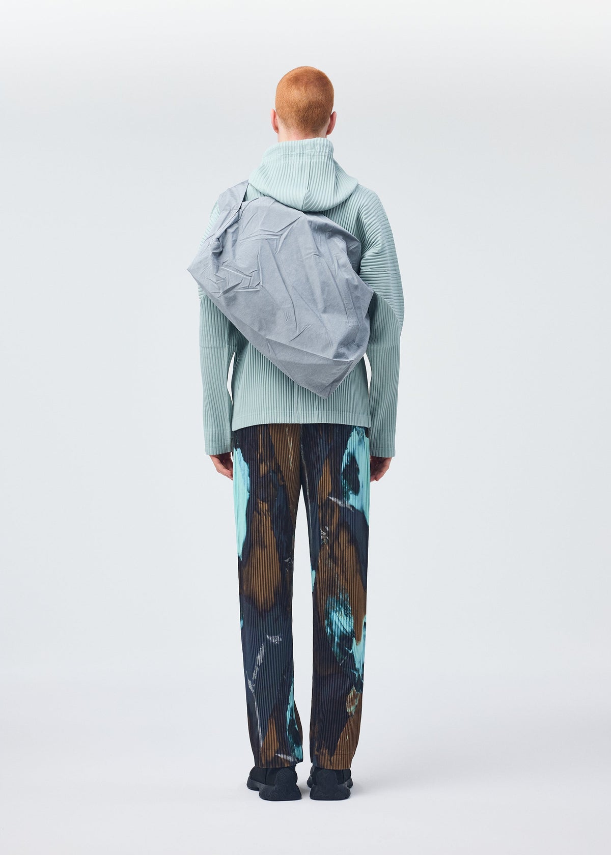 A model wears the HOMME PLISSÉ ISSEY MIYAKE STONE BAG bag.