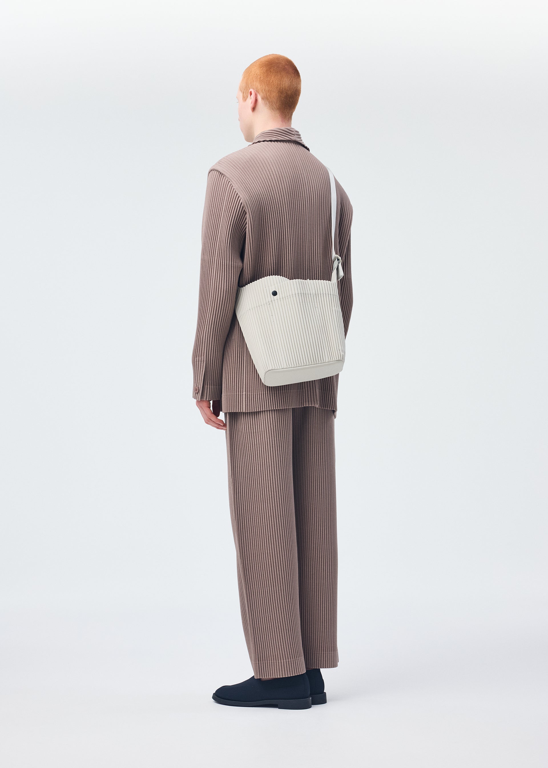 A model wears the HOMME PLISSÉ ISSEY MIYAKE UTILITY bag.