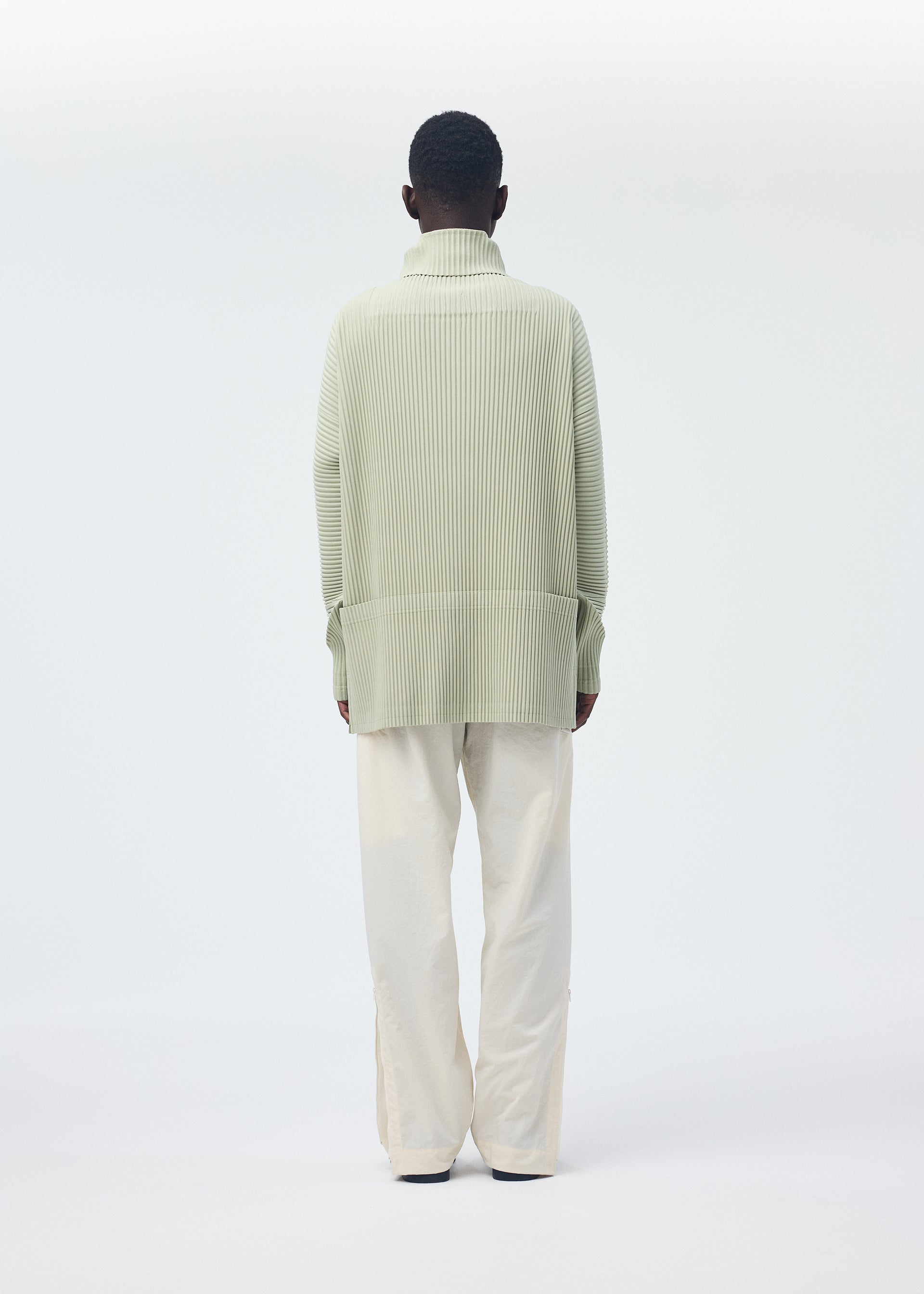 A model wears the HOMME PLISSÉ ISSEY MIYAKE QUARRY PANTS trousers.
