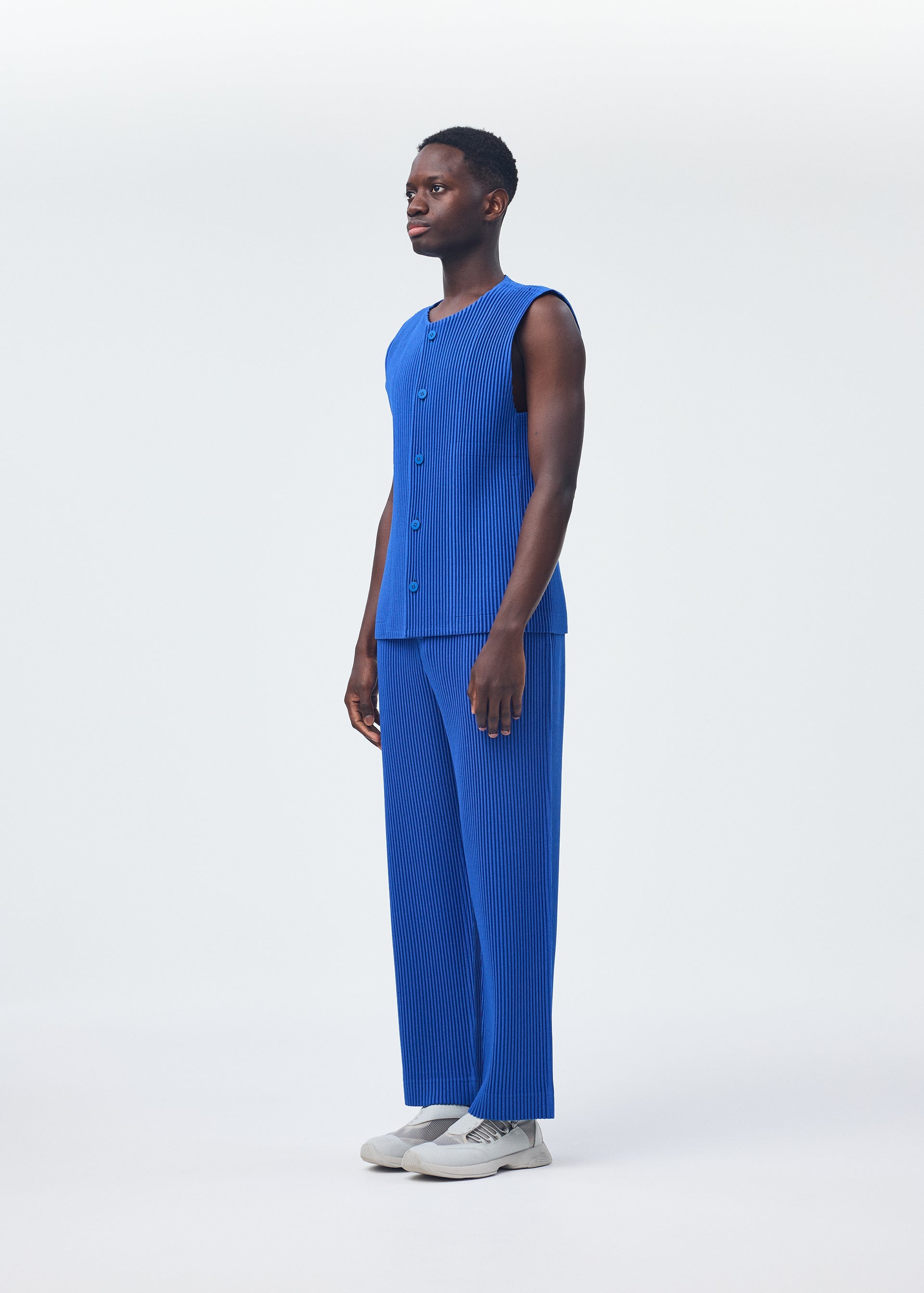 A model wears the HOMME PLISSÉ ISSEY MIYAKE KERSEY PLEATS trousers.
