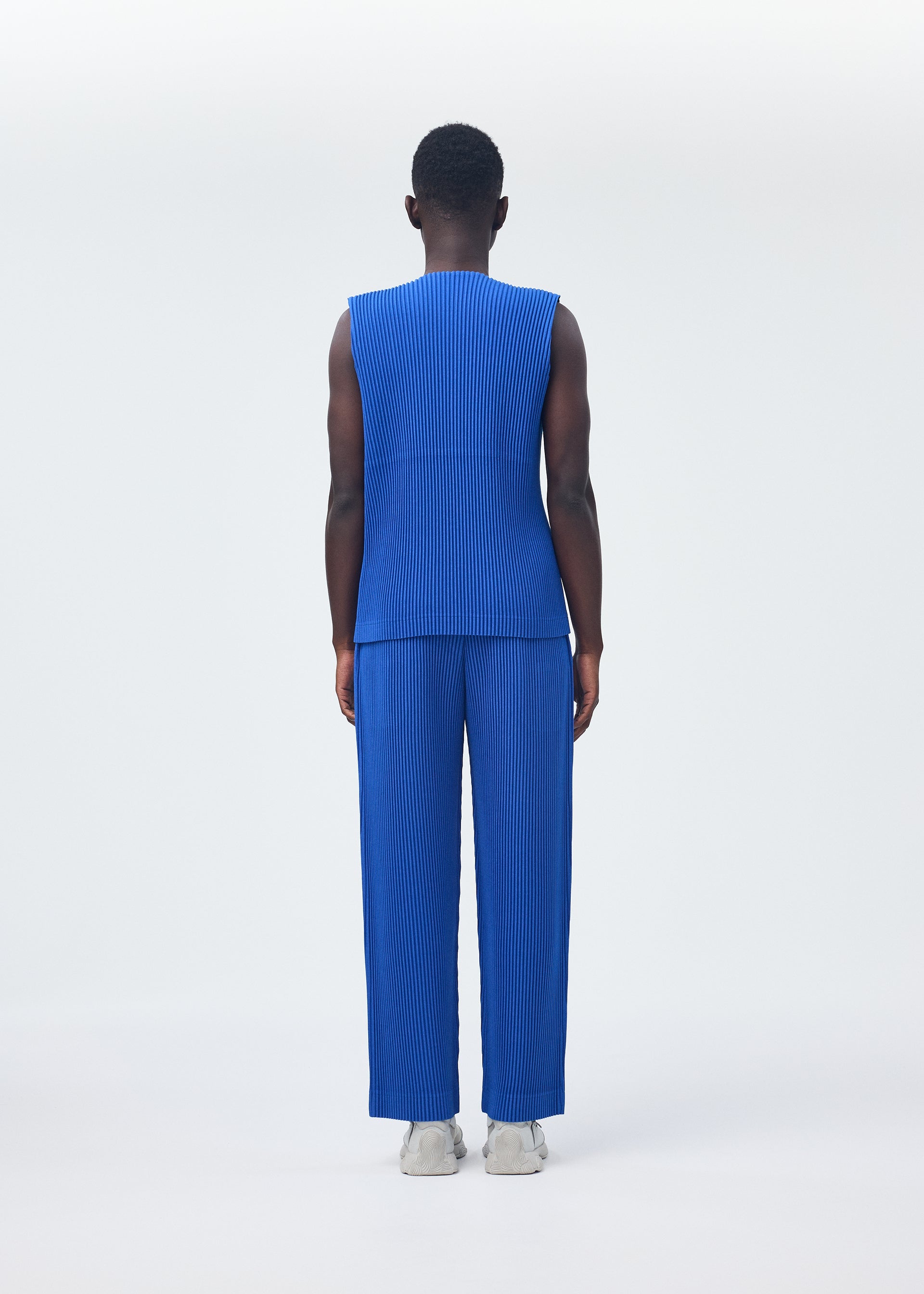 A model wears the HOMME PLISSÉ ISSEY MIYAKE KERSEY PLEATS trousers.