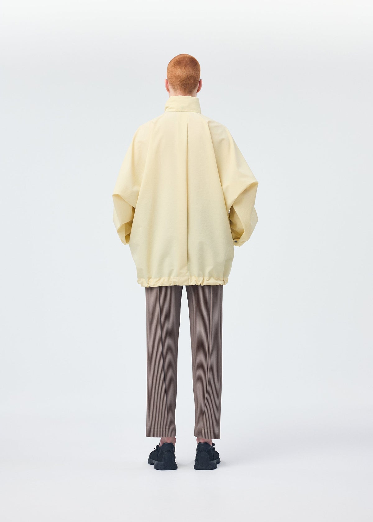 A model wears the HOMME PLISSÉ ISSEY MIYAKE PADDED RIM SHIRT shirt.