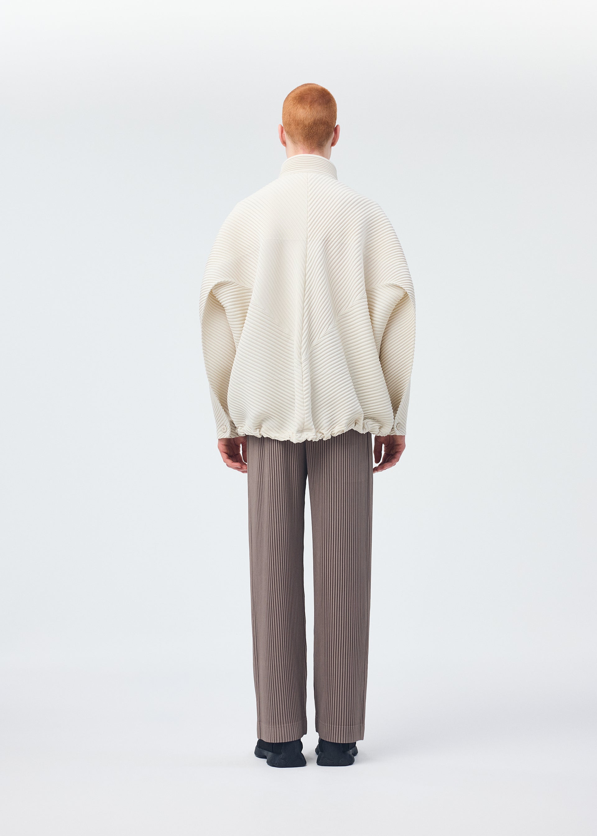 A model wears the HOMME PLISSÉ ISSEY MIYAKE MONTHLY COLORS SEPTEMBER trousers.