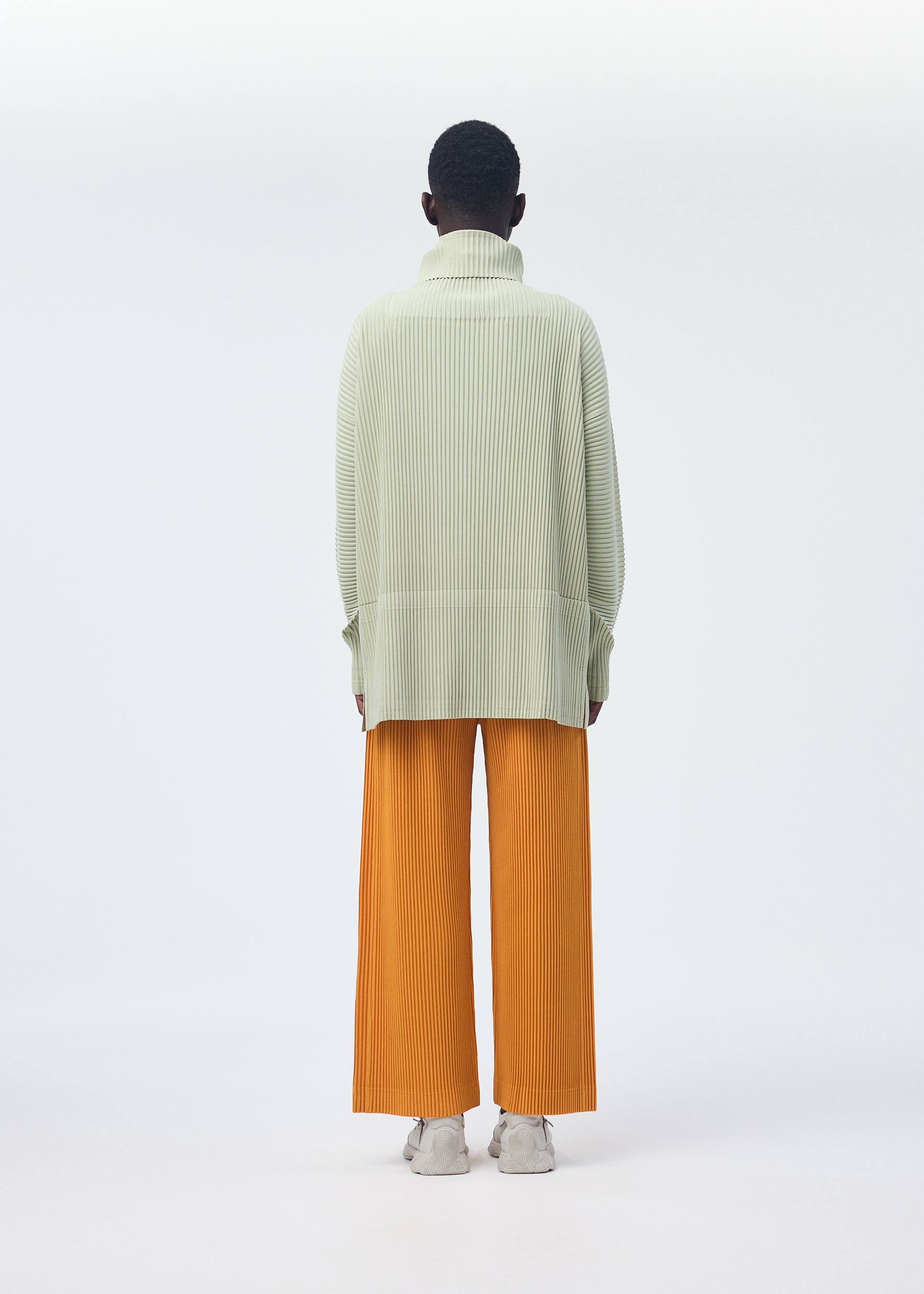 A model wears the HOMME PLISSÉ ISSEY MIYAKE MONTHLY COLORS OCTOBER trousers.