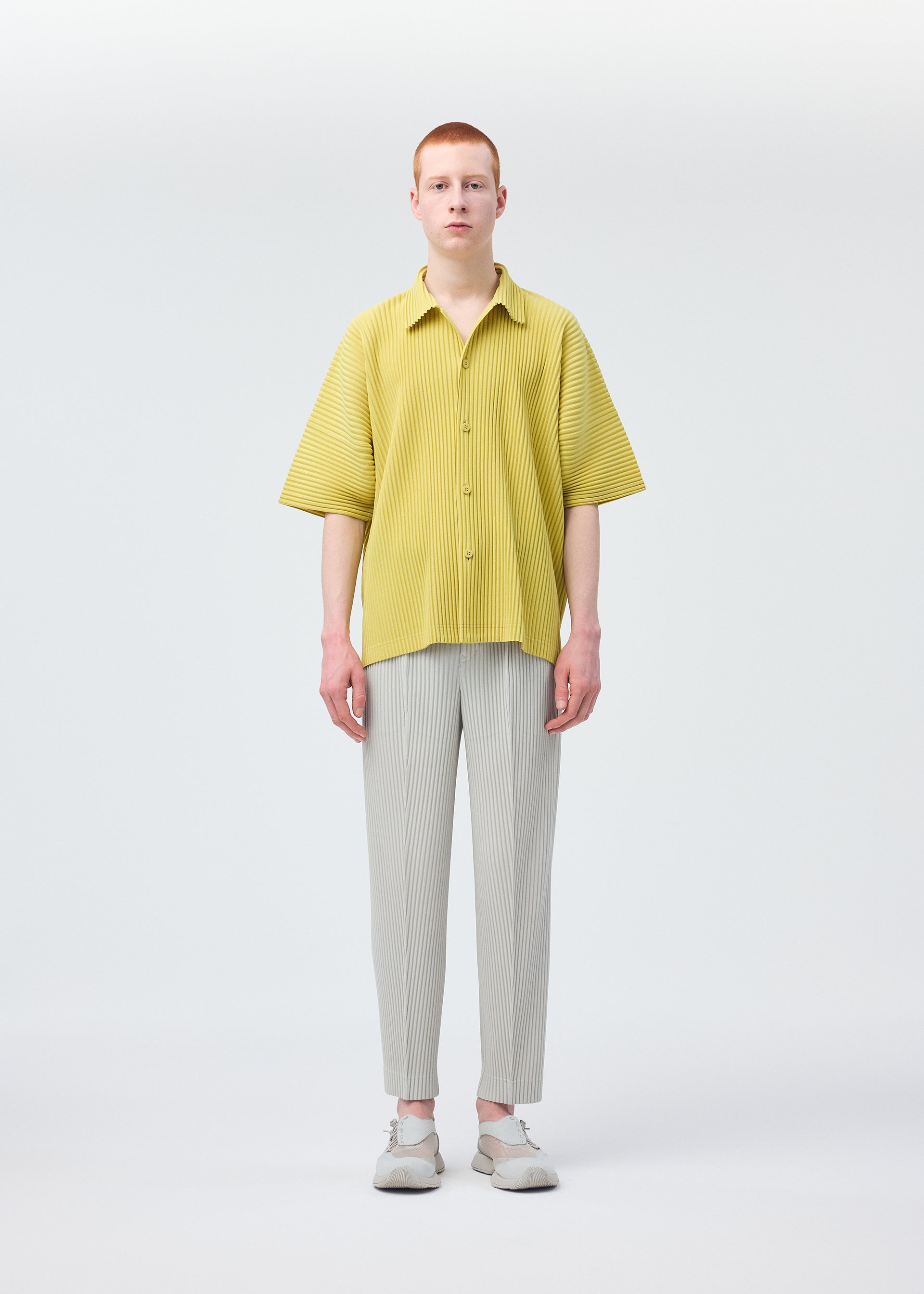 A model wears the HOMME PLISSÉ ISSEY MIYAKE COMPLEAT TROUSERS trousers.