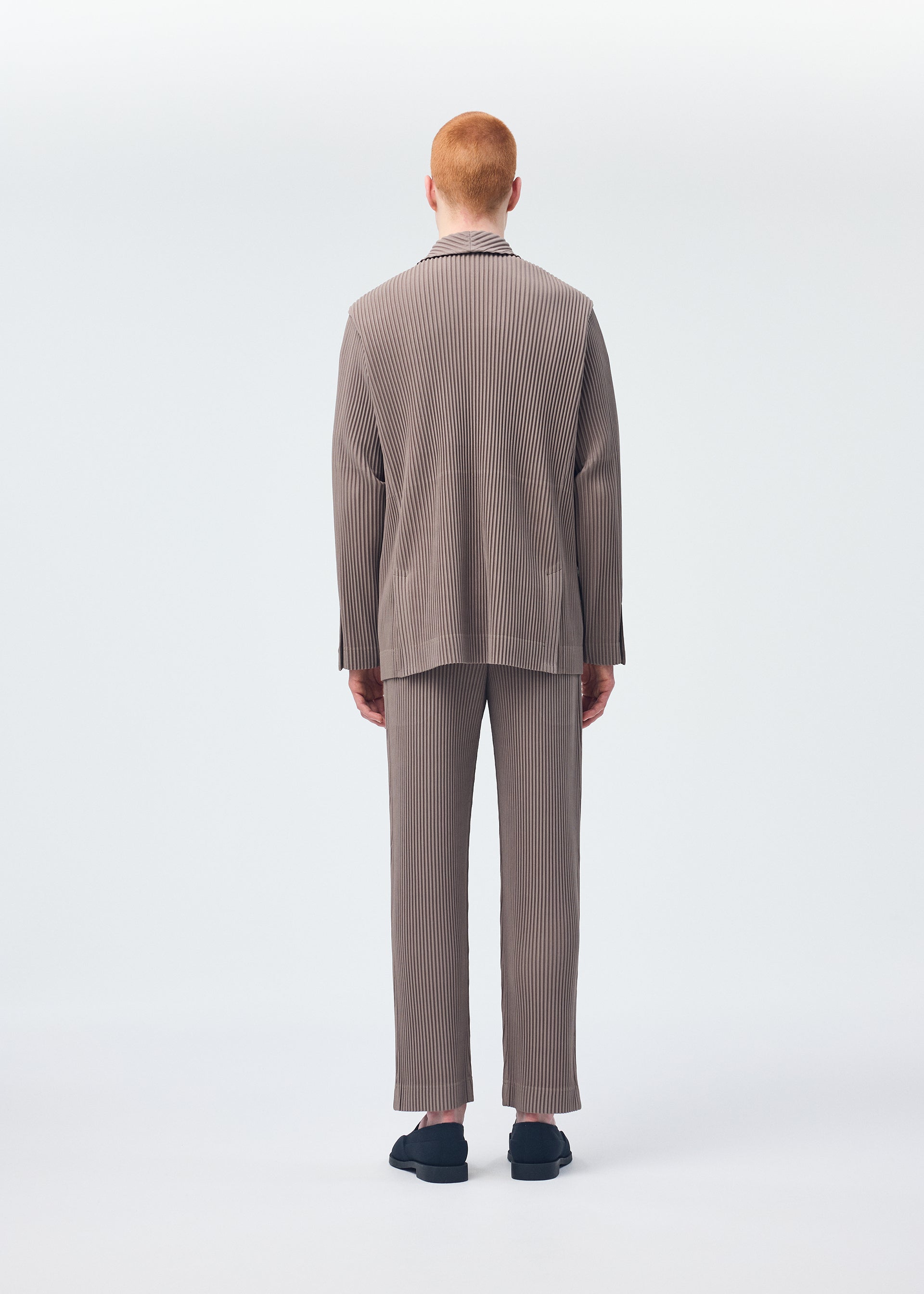 A model wears the HOMME PLISSÉ ISSEY MIYAKE TAILORED PLEATS 1 trousers.