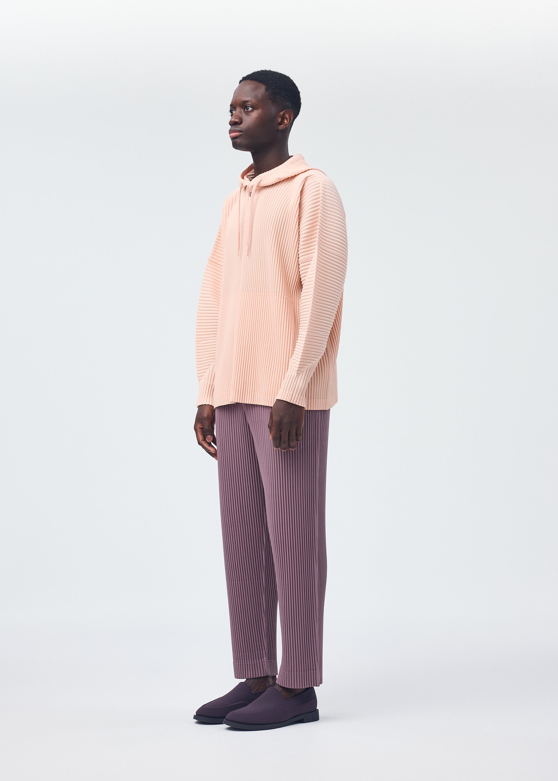 A model wears the HOMME PLISSÉ ISSEY MIYAKE COLOR PLEATS trousers.