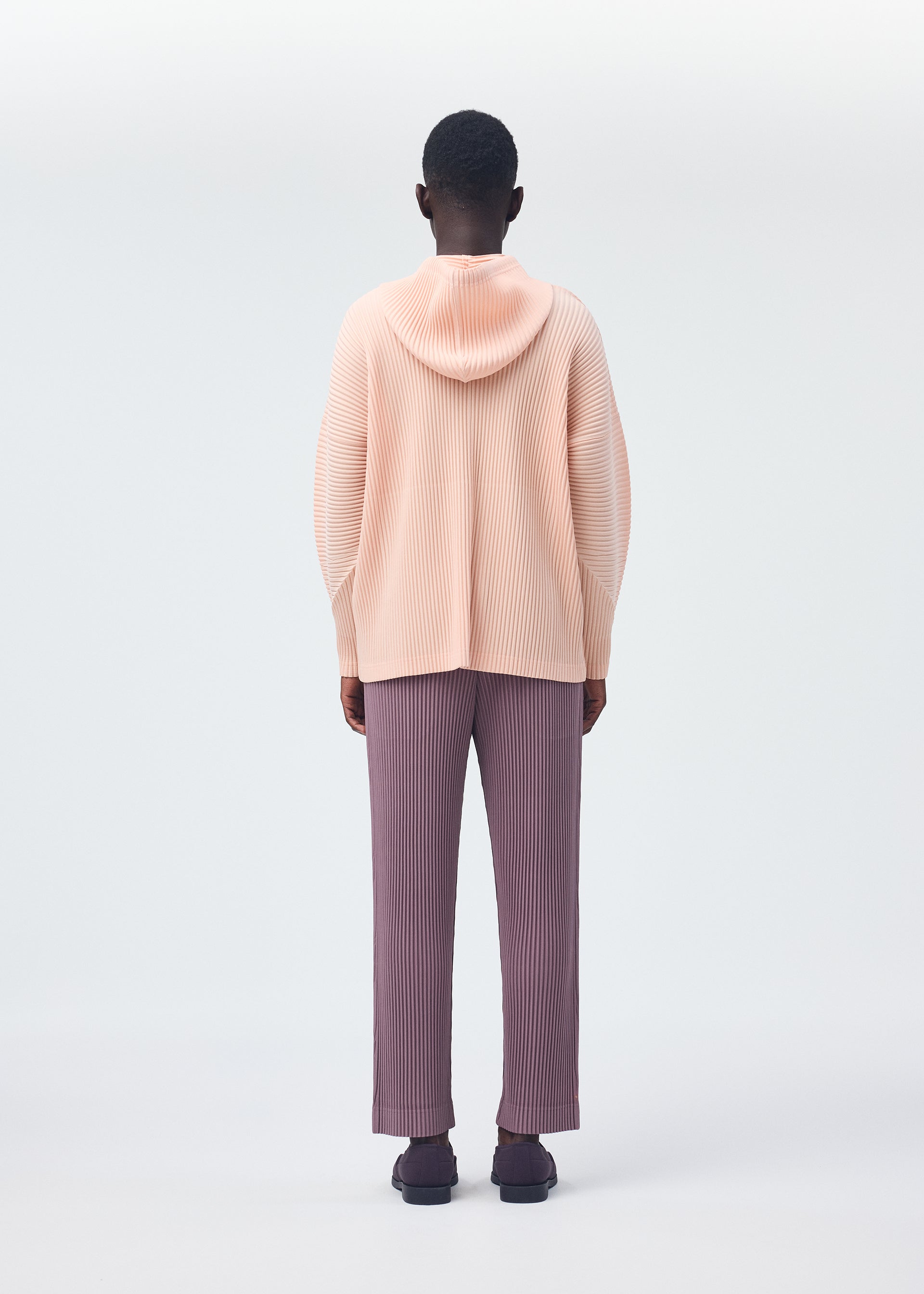 A model wears the HOMME PLISSÉ ISSEY MIYAKE COLOR PLEATS trousers.