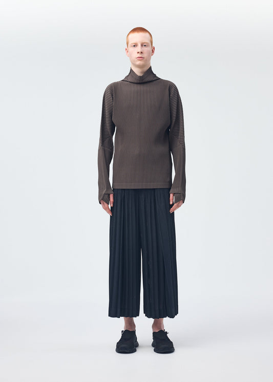 A model wears the HOMME PLISSÉ ISSEY MIYAKE WICKERWORK MESH trousers.