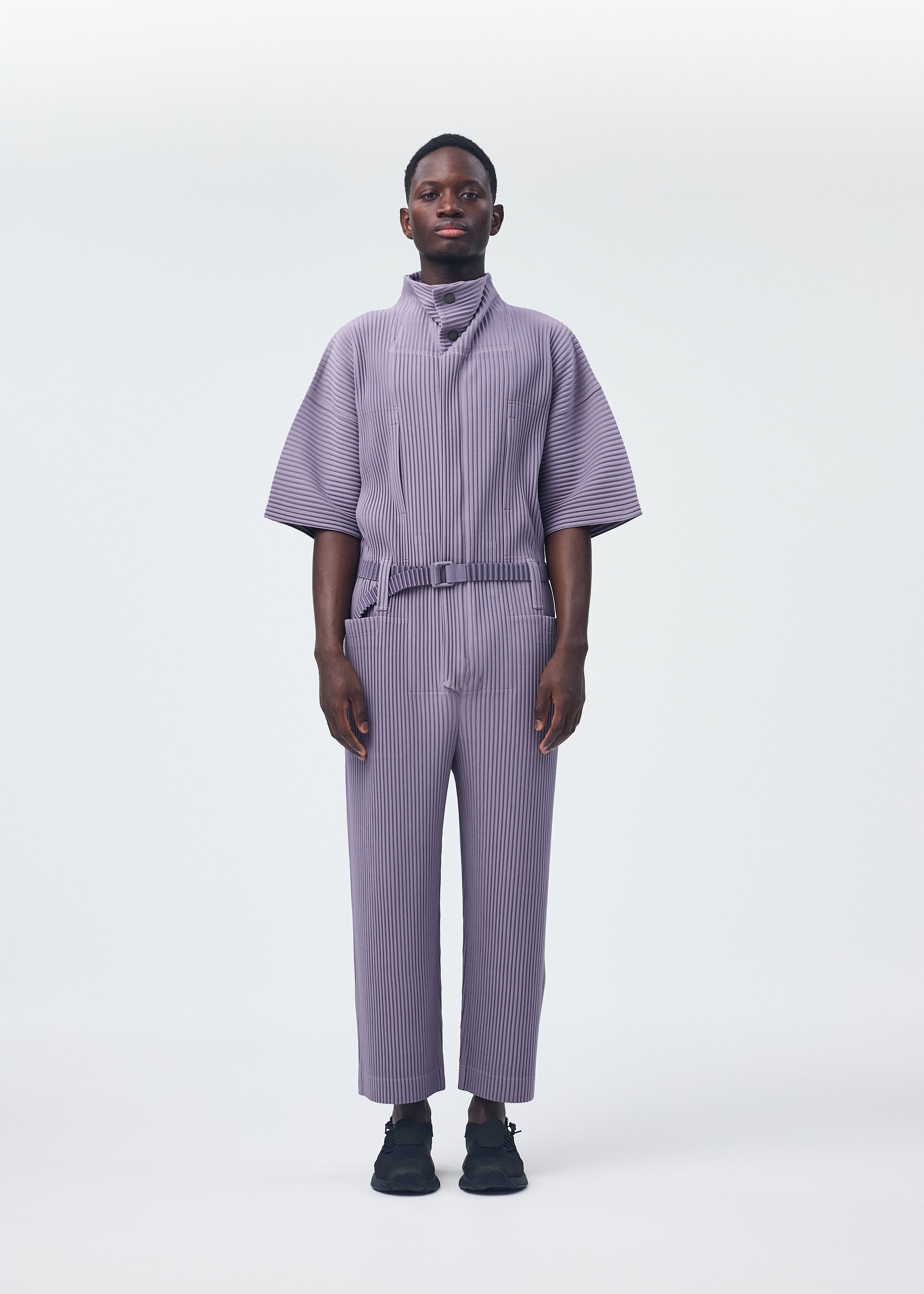 A model wears the HOMME PLISSÉ ISSEY MIYAKE PLEATS BOTTOMS 1 jumpsuit.